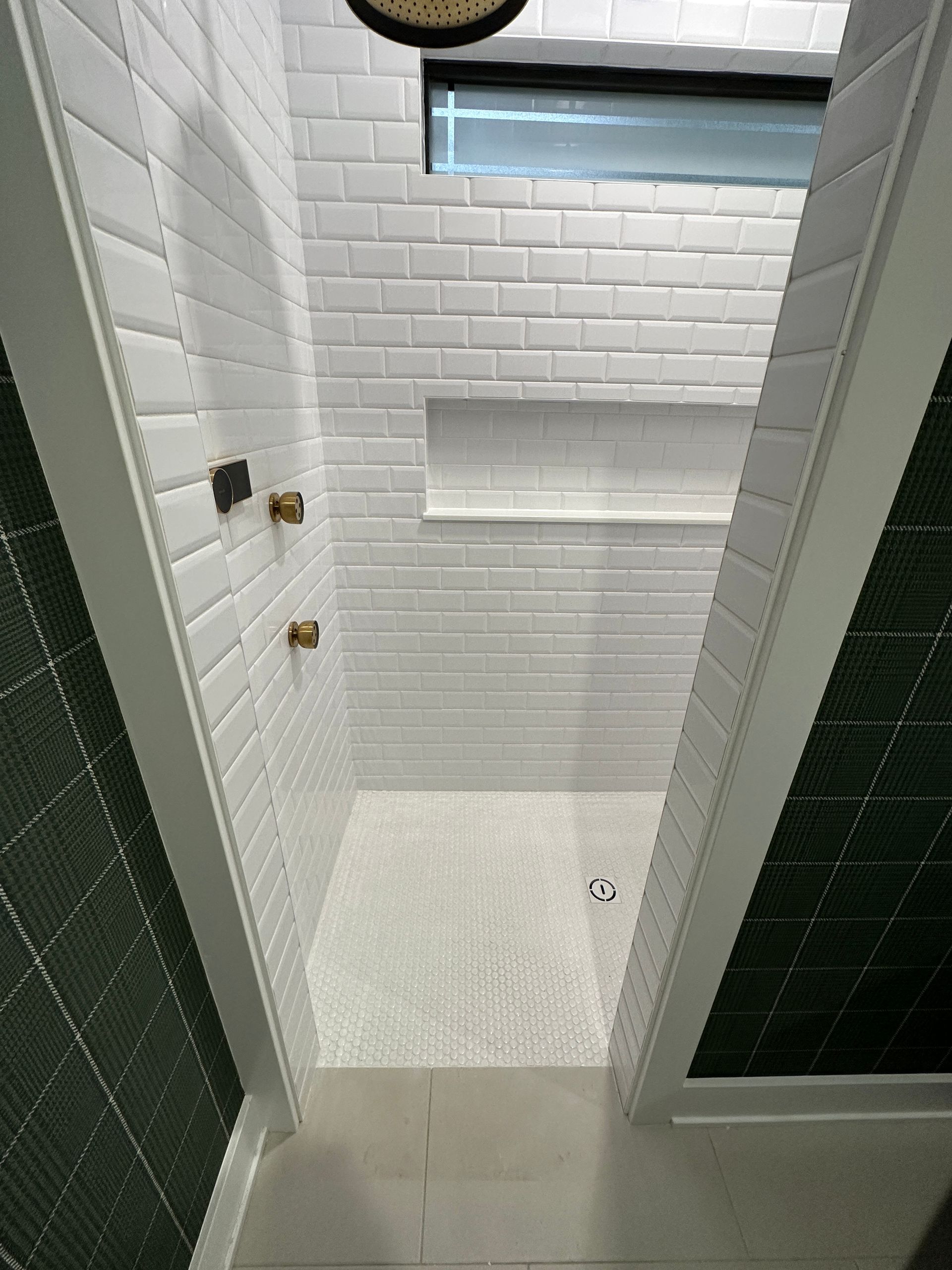 A bathroom with white tiles and green tiles and a walk in shower.