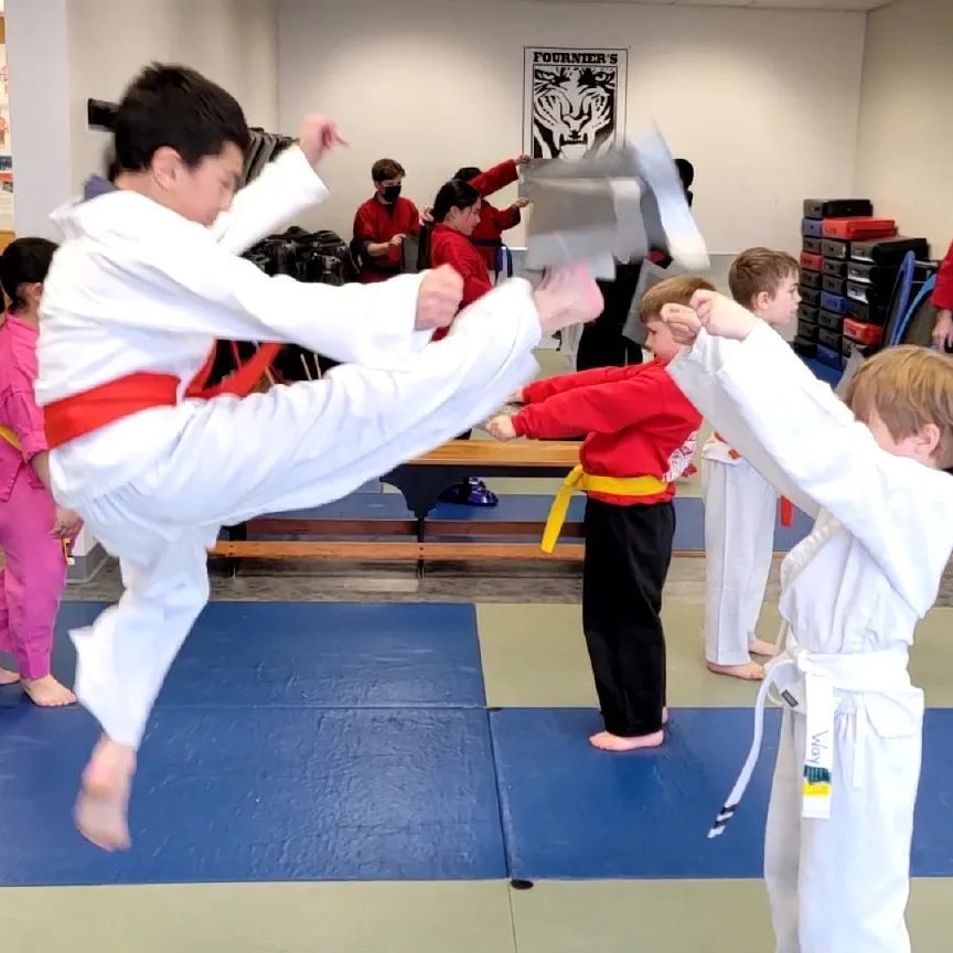 A group of kids are practicing martial arts in a gym