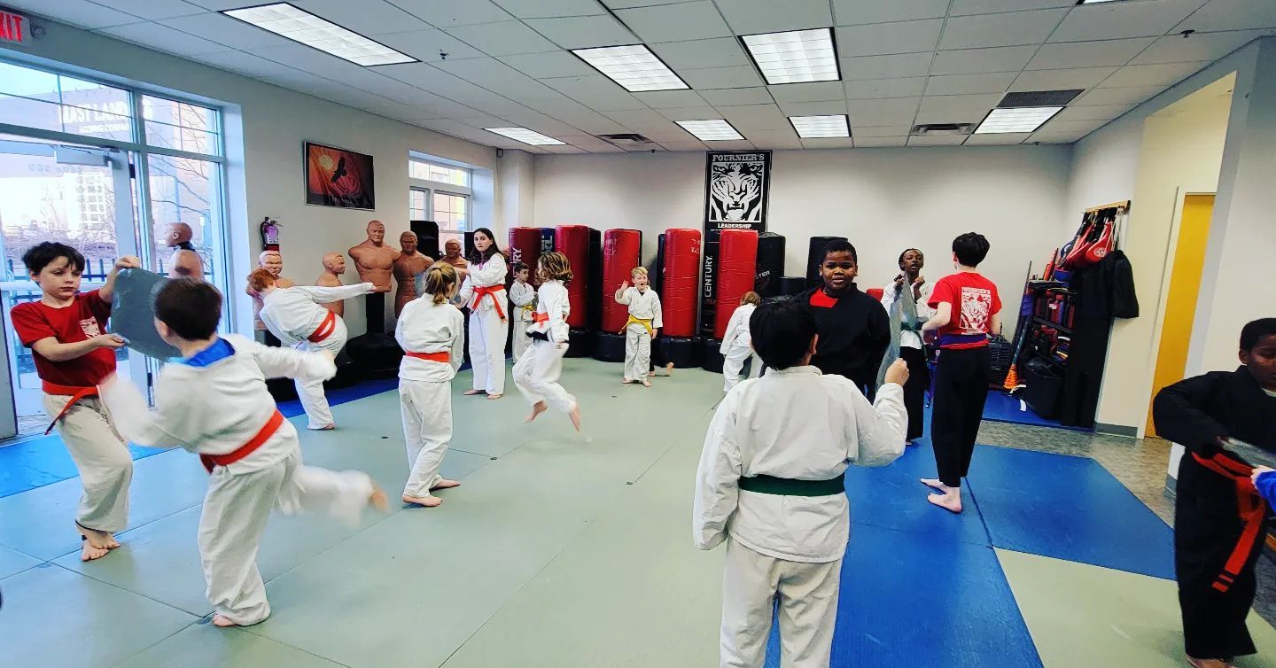 A group of children are practicing martial arts in a gym.