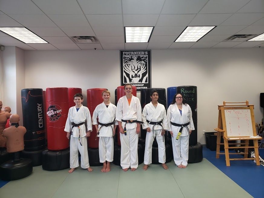 A group of people in karate uniforms are standing next to each other in a gym.
