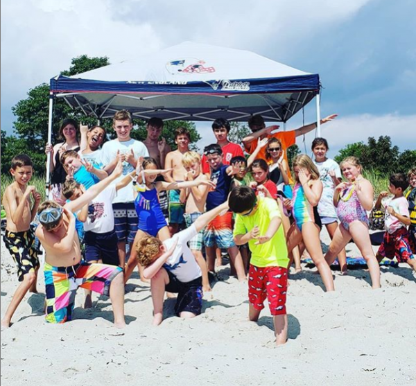 A group of kids are posing for a picture on the beach