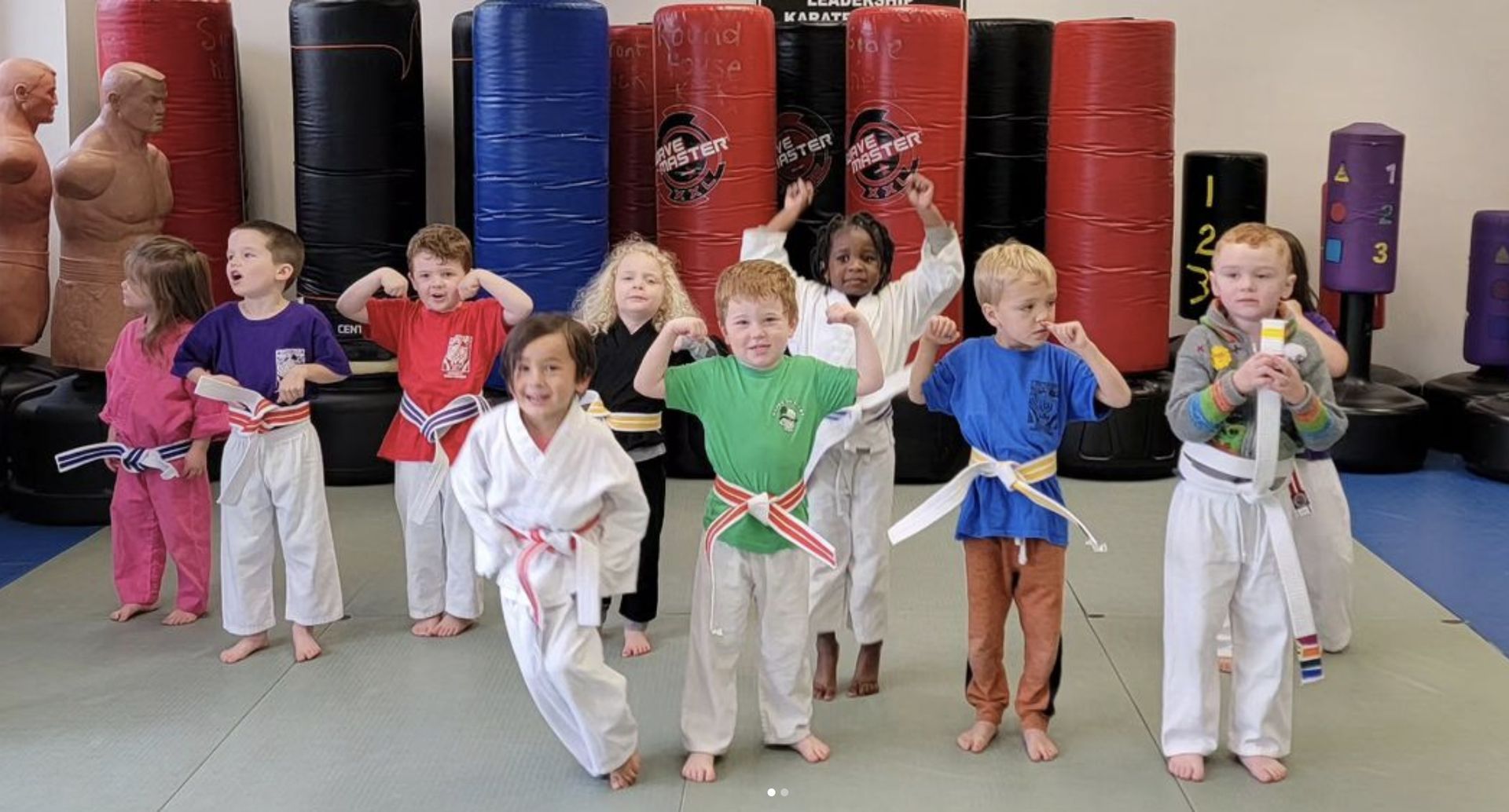 A group of young children are practicing martial arts in a gym.