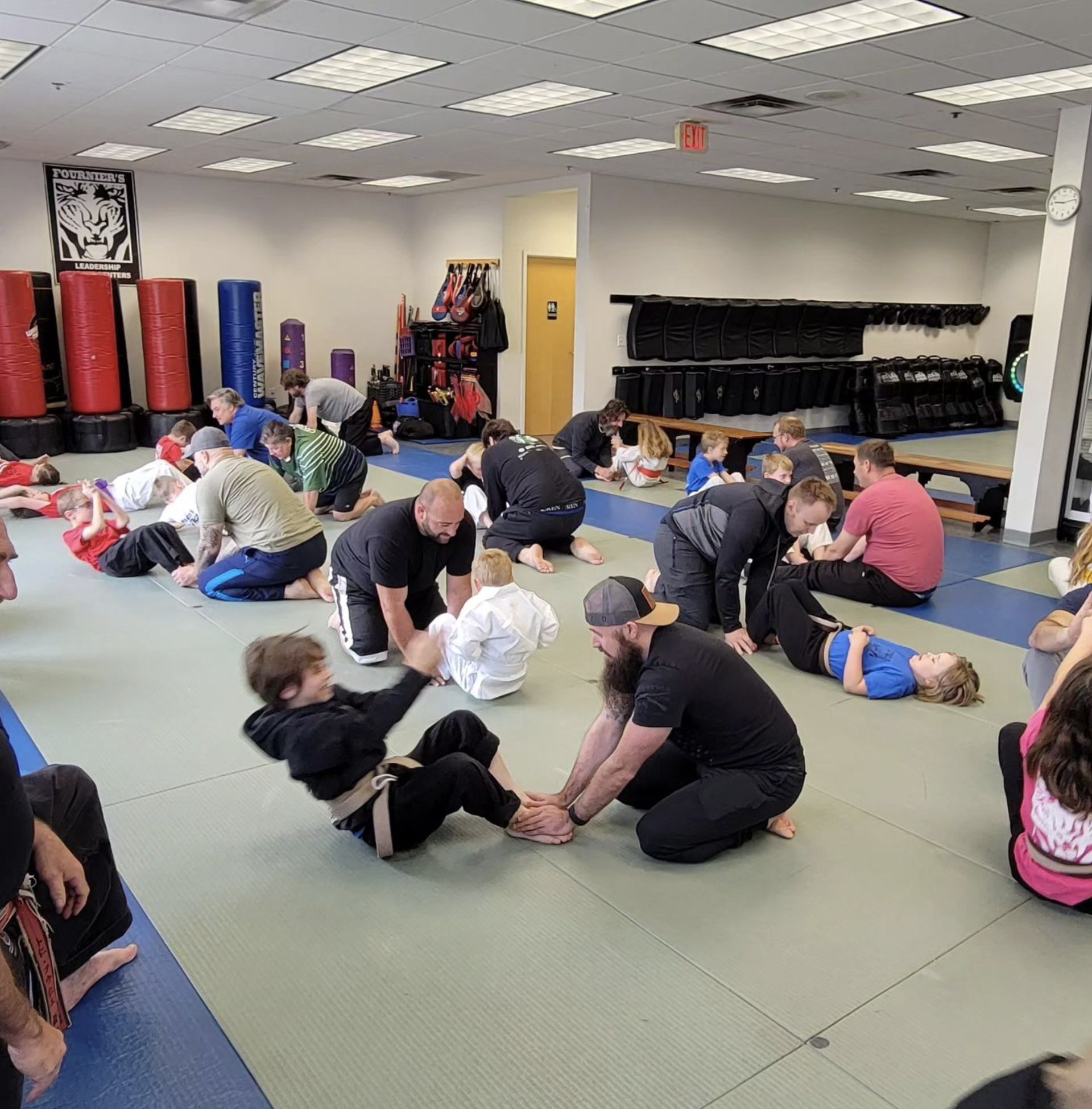 A group of people are sitting on the floor in a gym.