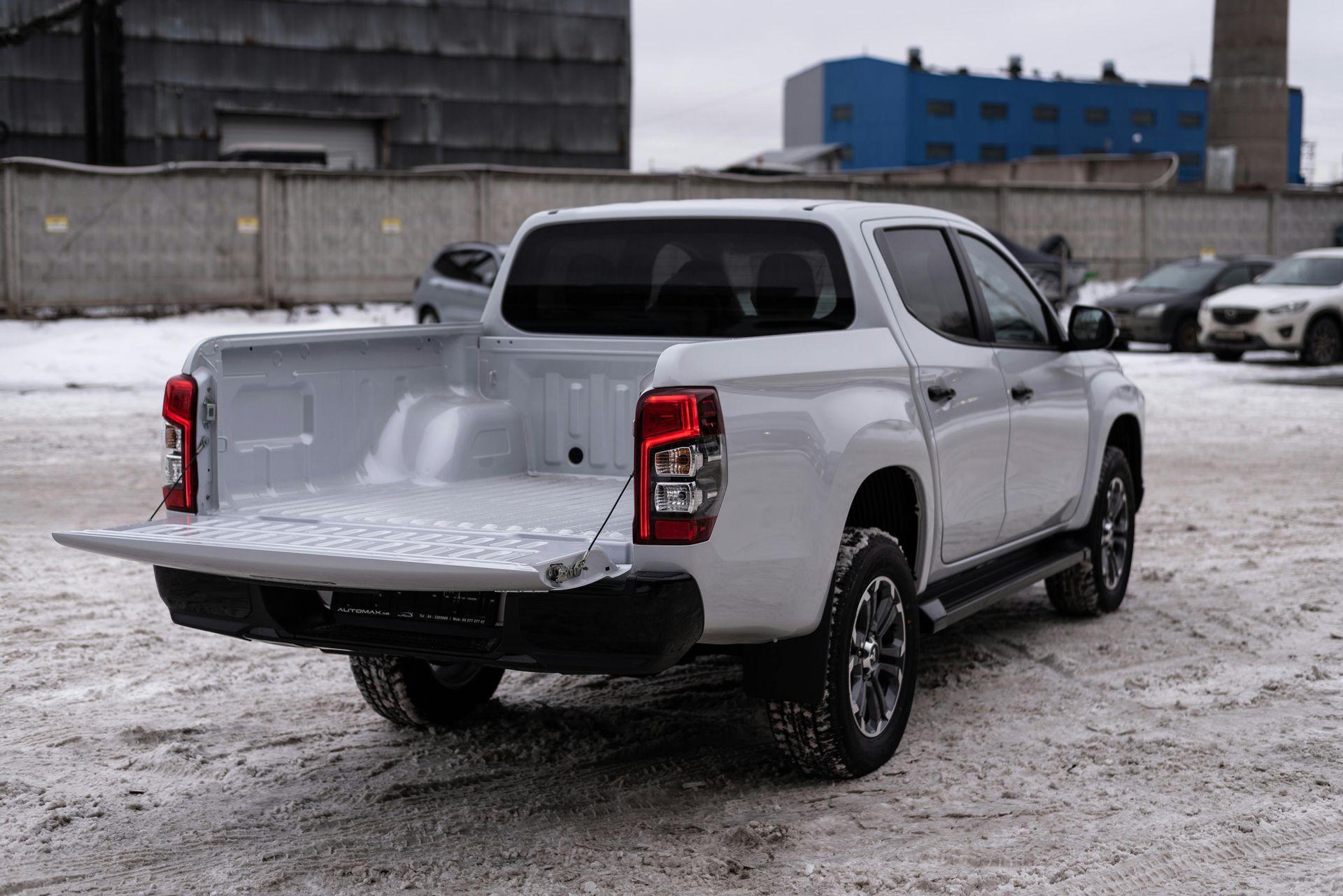White pickup truck with the tailgate open, parked on snow-covered ground.