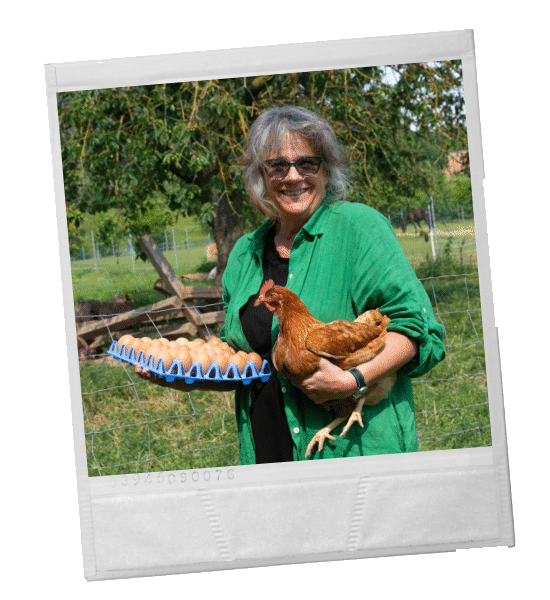 Frau hält ein Huhn und einen Eierkarton in sonniger Außenumgebung.