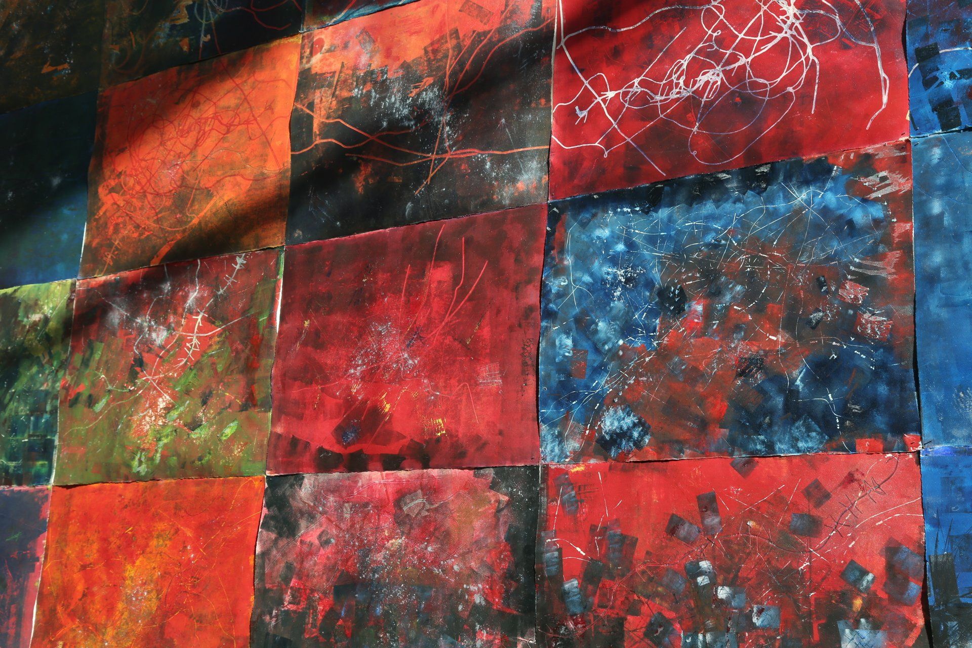 Abstract artwork composed of colorful, textured squares; reds, blues, greens, and whites create a patchwork effect.