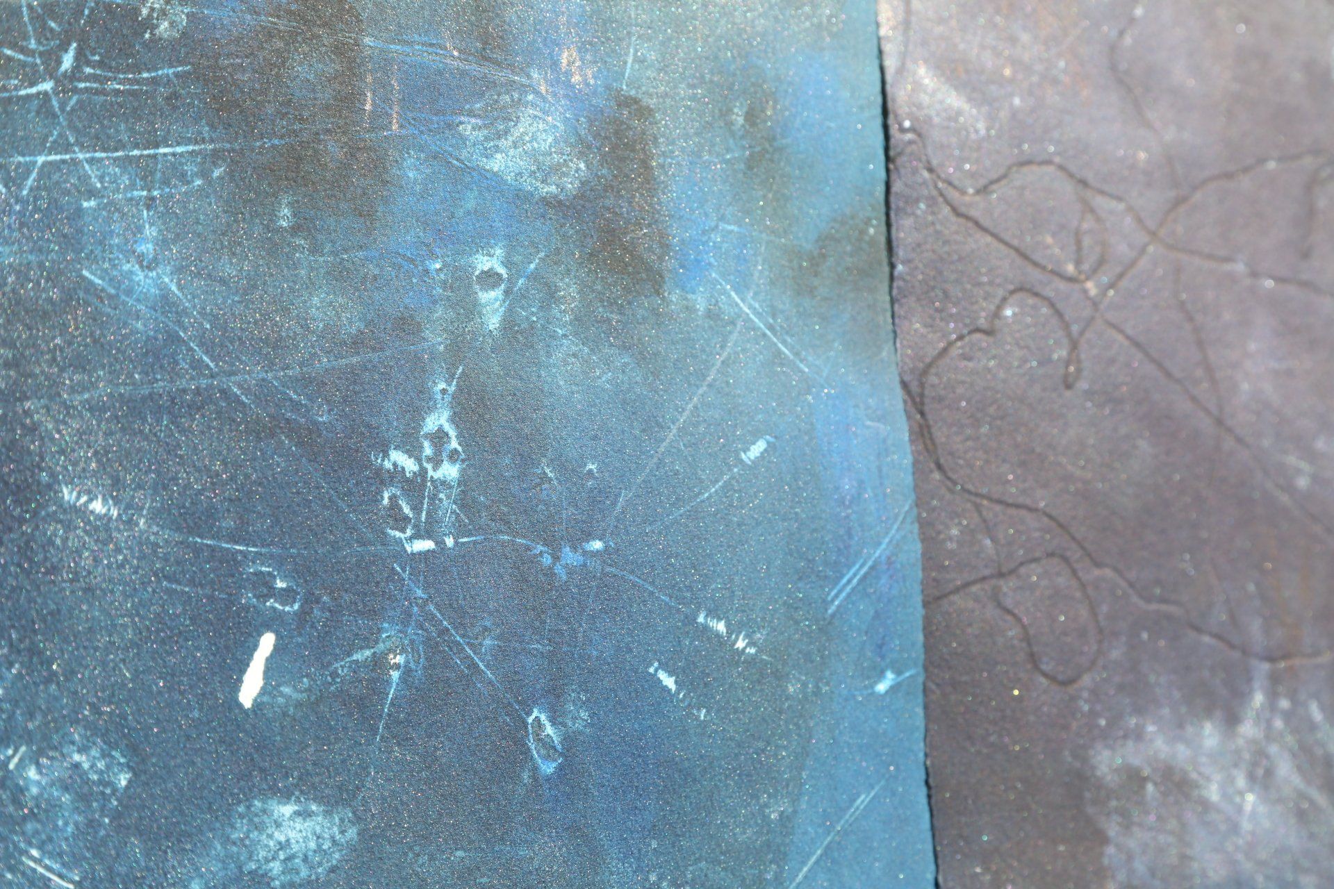 Blue and black textured surfaces with scratches and faint white marks.