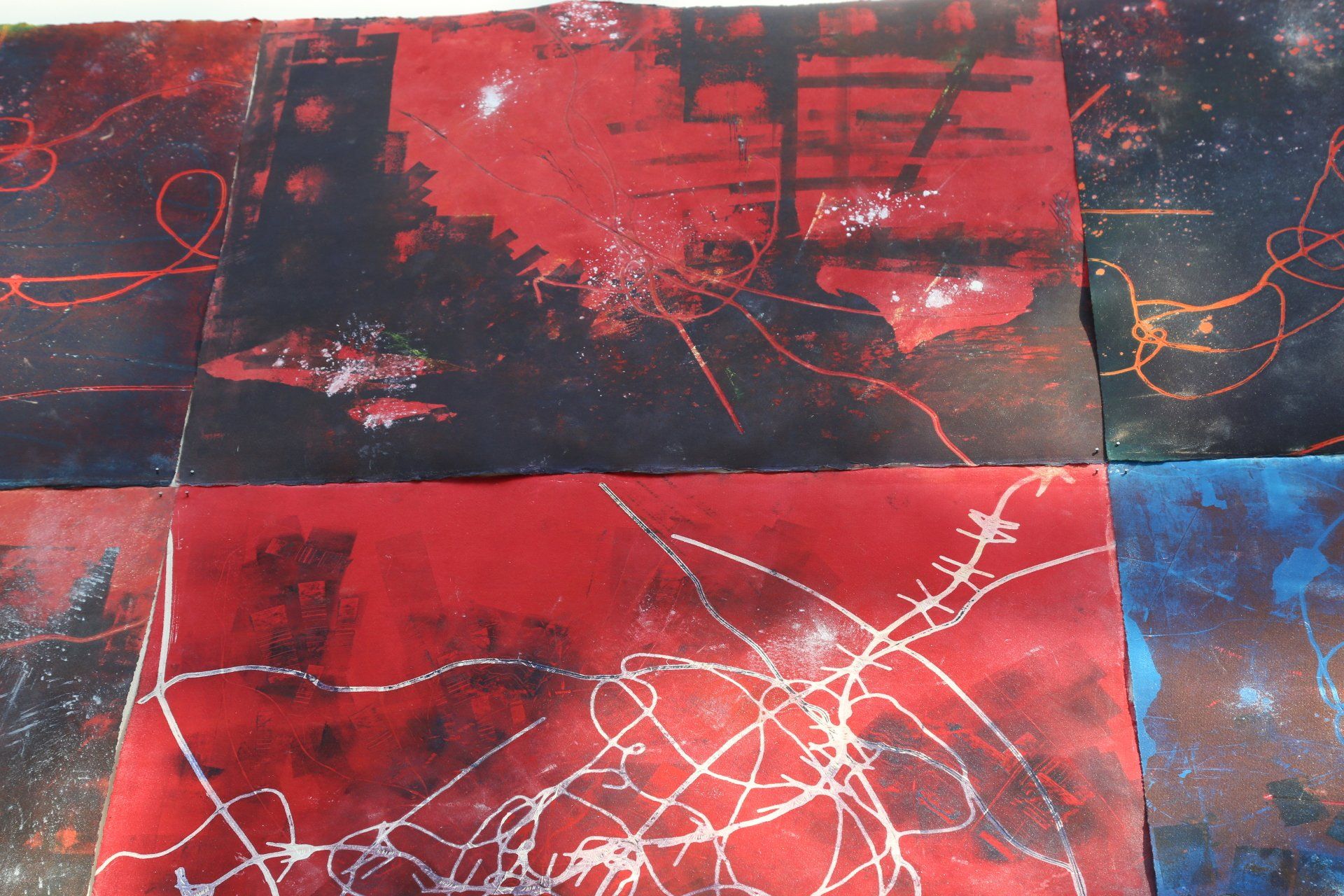 Red and black abstract art with white lines and speckles, arranged in a grid.