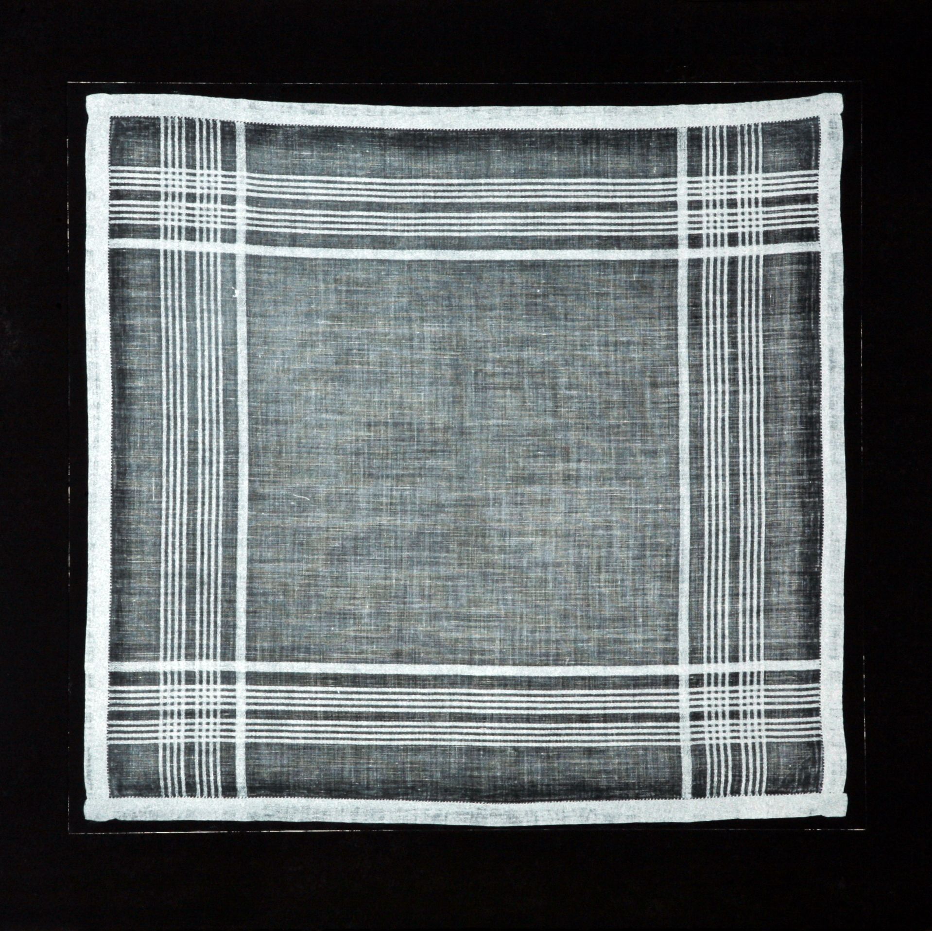 White handkerchief with a grid pattern against a black background.