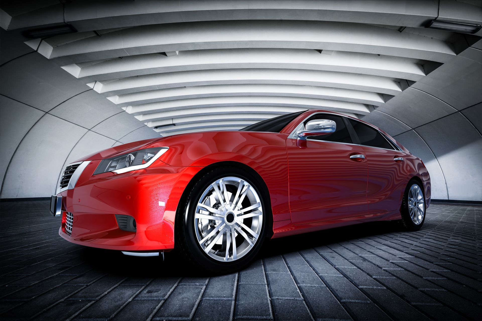 Red sedan in a modern tunnel-like showroom, viewed from the front side angle.