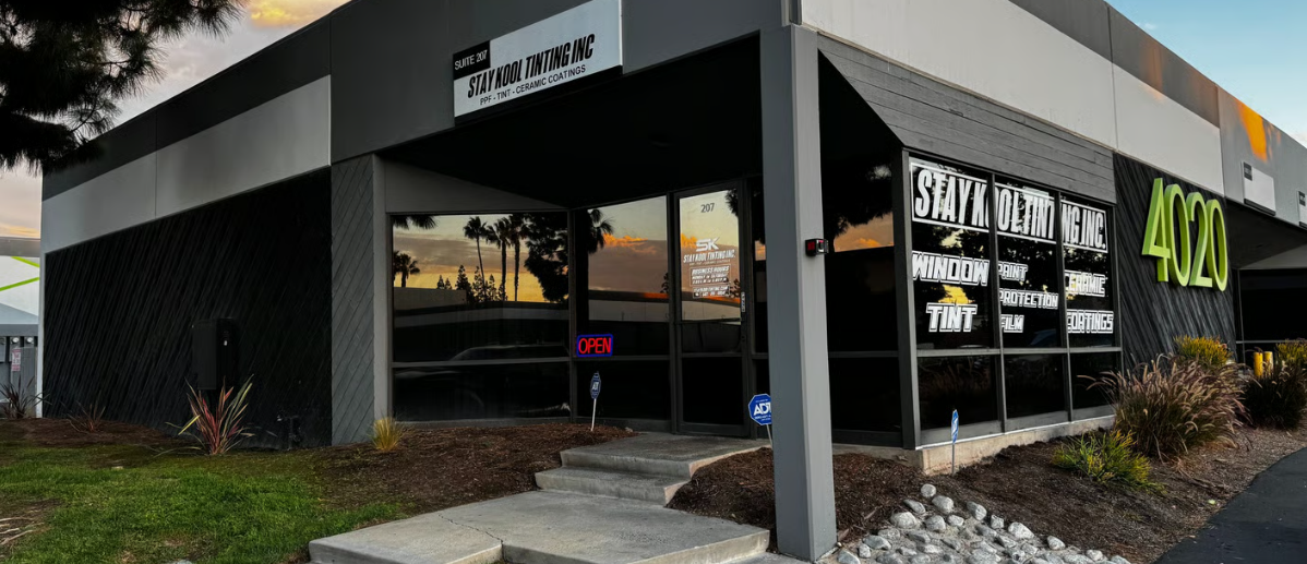 Modern storefront with black exterior, large windows, and neon signage at dusk