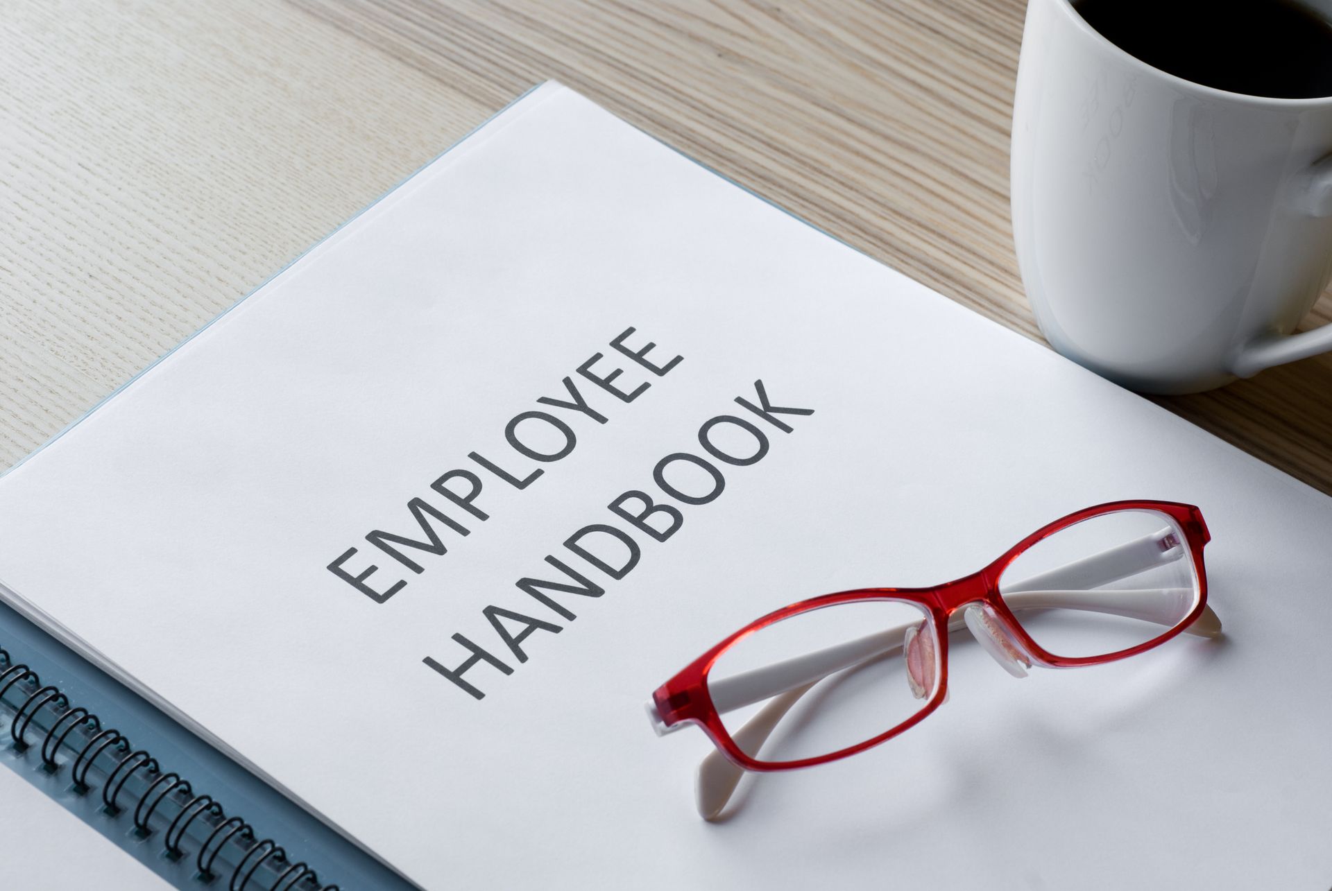 A pair of glasses sits on top of an employee handbook