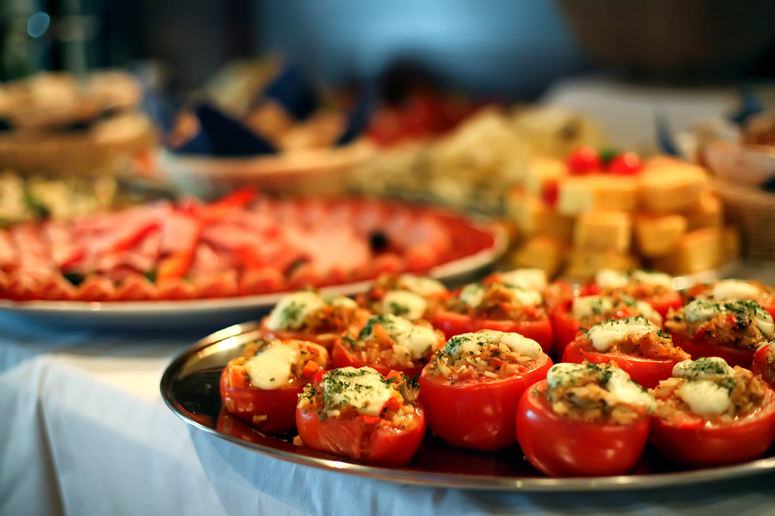 A tray of stuffed tomatoes is on a table with other food.