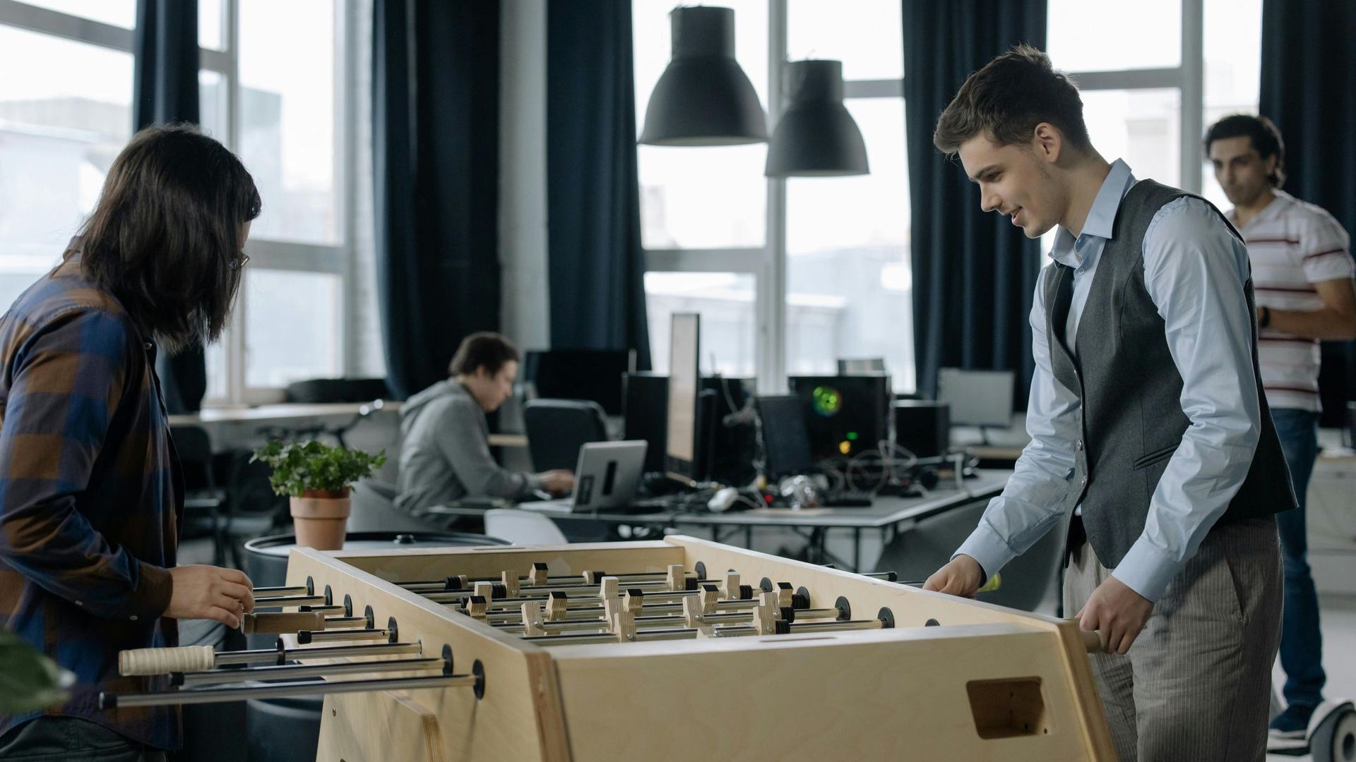 A man and a woman are playing foosball in an office.