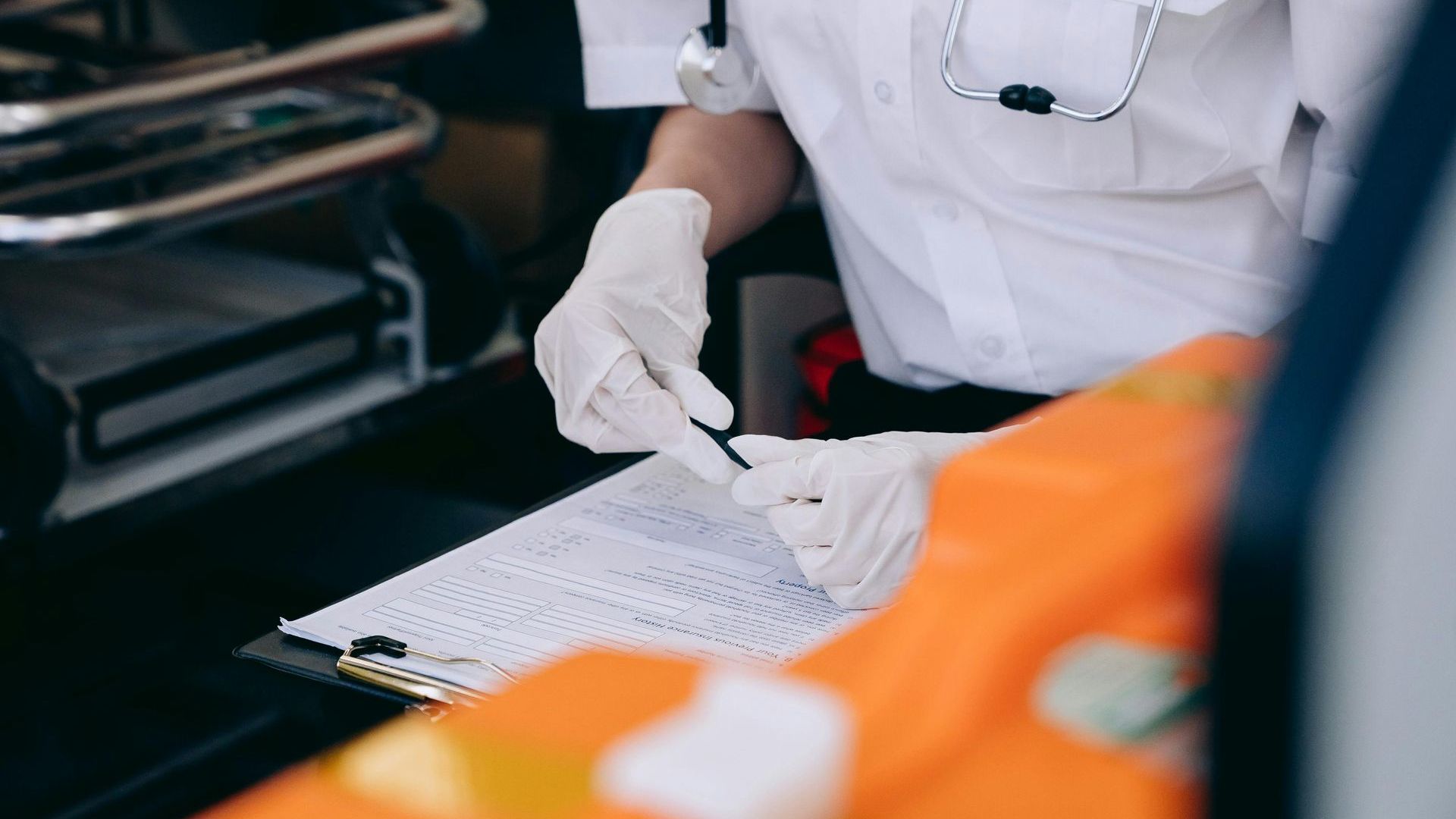 A paramedic is writing on a clipboard in an ambulance.