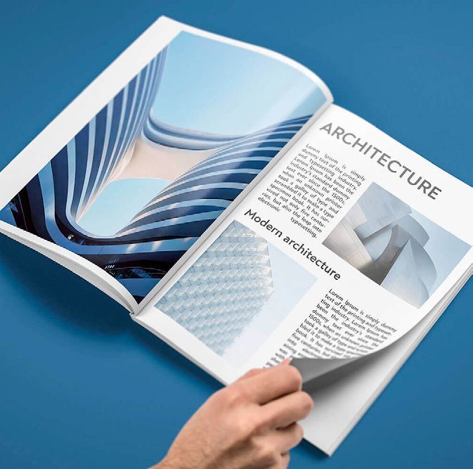 Eine Person blättert in einer Zeitschrift mit Architekturfotos auf blauem Untergrund.