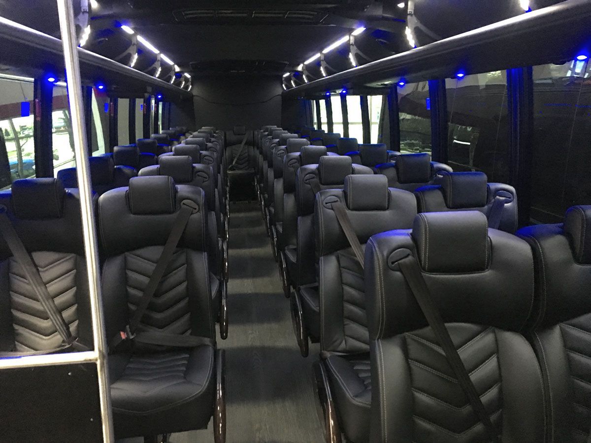 The inside of a bus with black seats and blue lights.