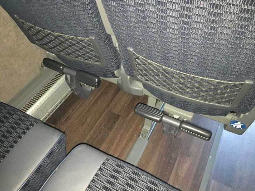 A close up of a seat with a foot rest on a wooden floor