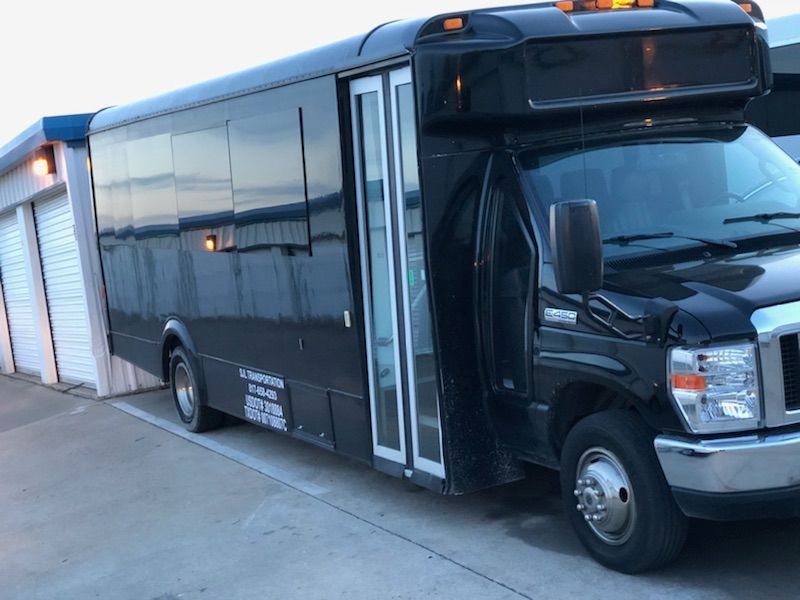 A black bus is parked in a parking lot next to a building.