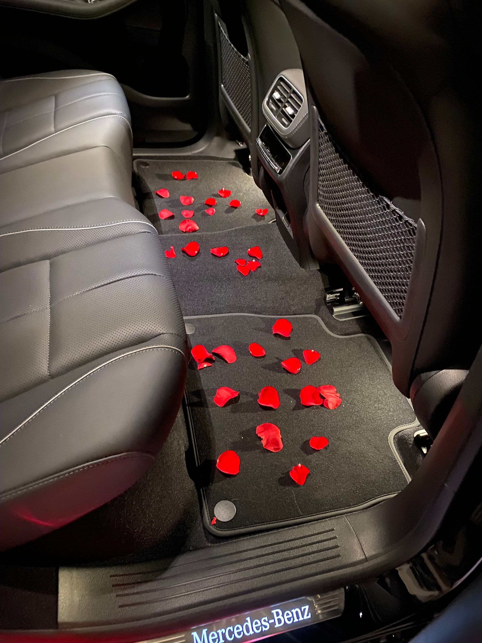 A mercedes benz car with red rose petals on the floor
