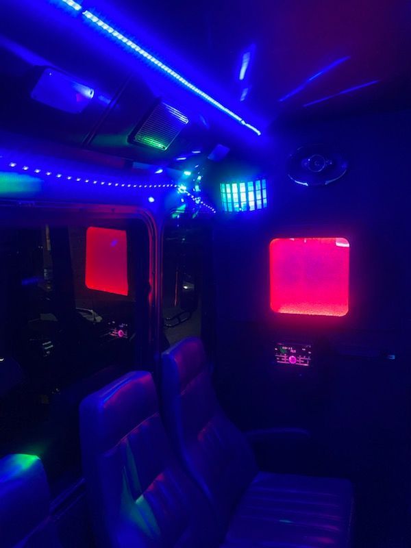 The inside of a bus with blue and red lights on the ceiling.