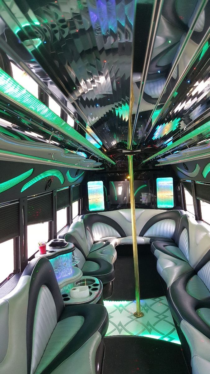 The inside of a limousine with lots of seats and a pole.