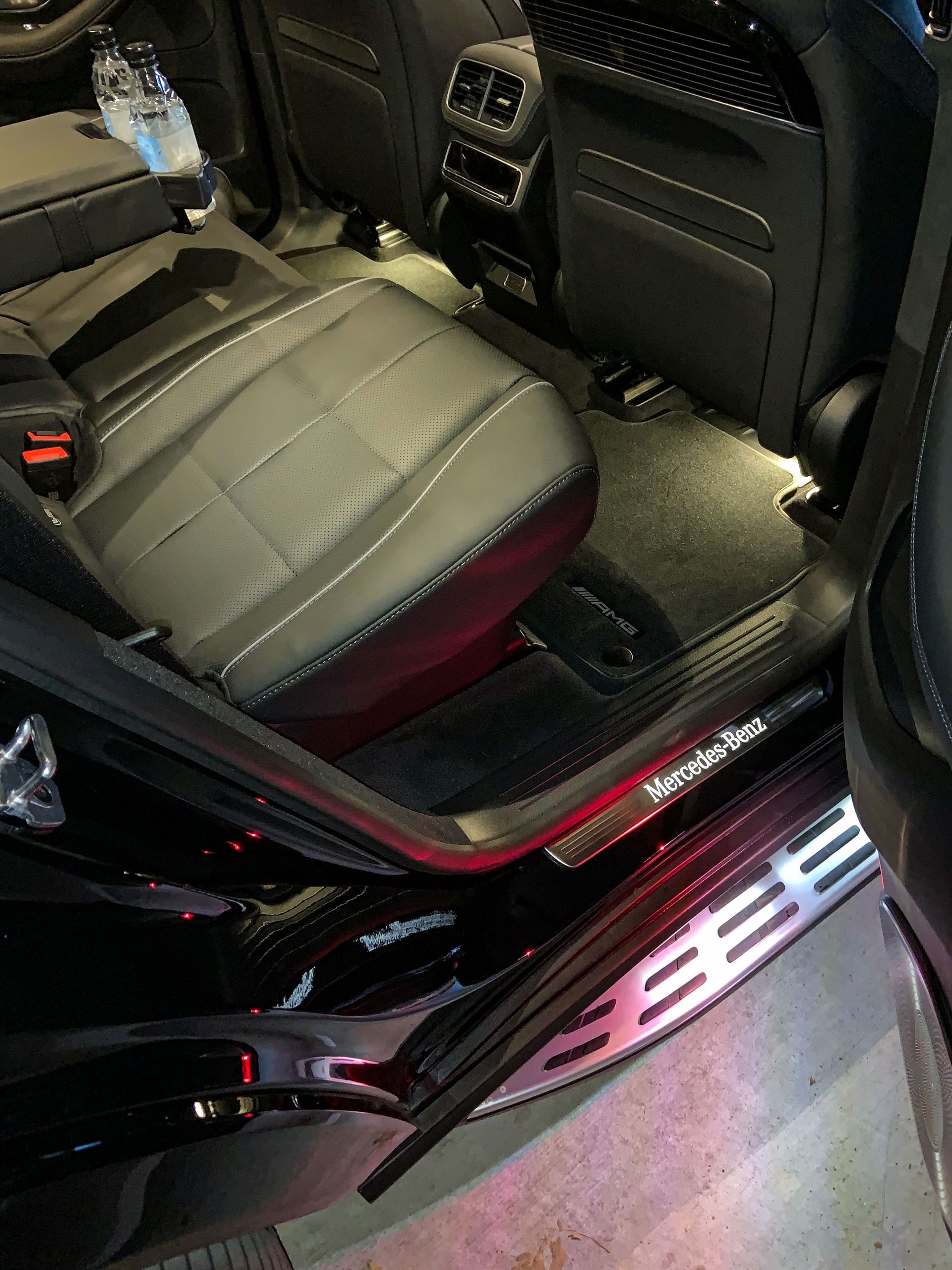 The back seat of a black car with the door open.