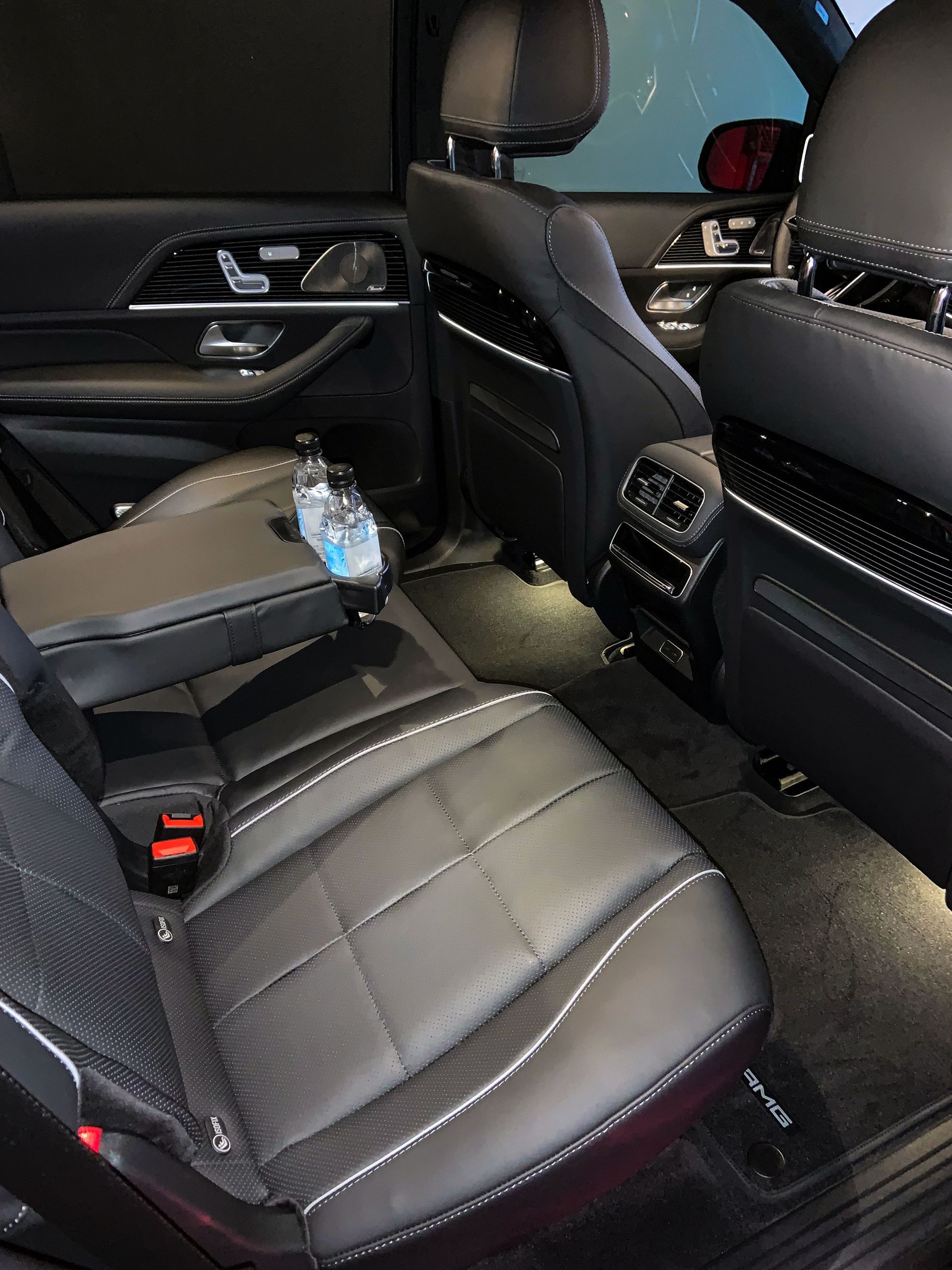 The interior of a car with black leather seats and a bottle of water in the center console.