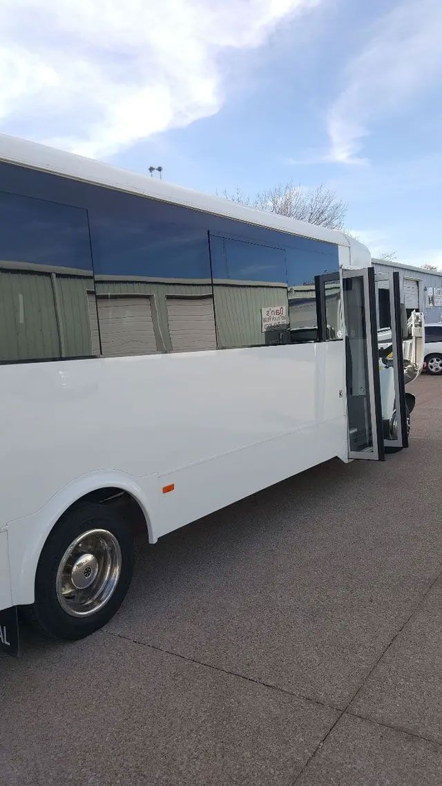 A white bus is parked in a parking lot with its doors open.