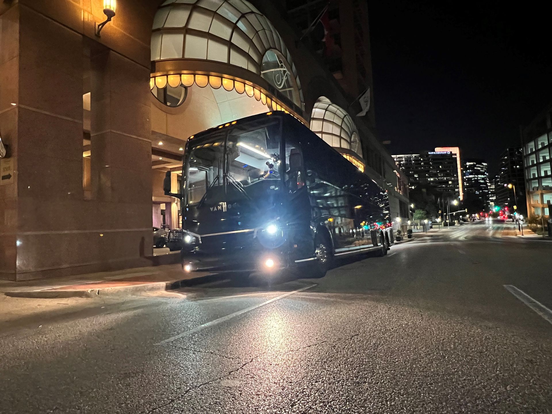 A black bus is driving down a city street at night.
