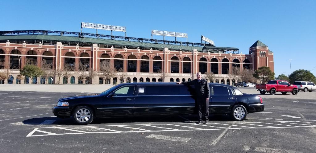 A man standing next to a black limousine in a parking lot