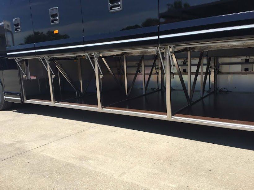 A large black bus with the trunk open is parked on the side of the road.