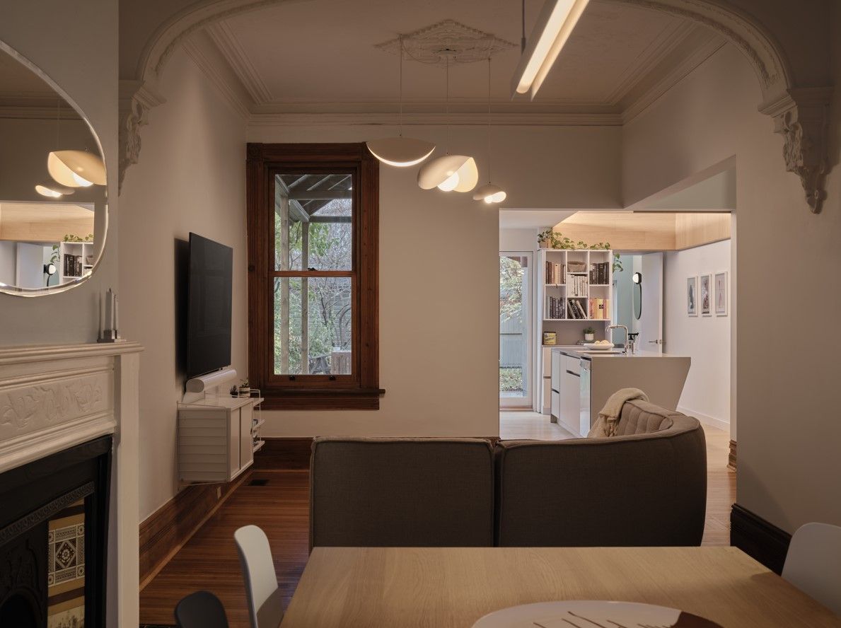 Living room with dark wood trim, TV, sofa, and a doorway to a kitchen area.