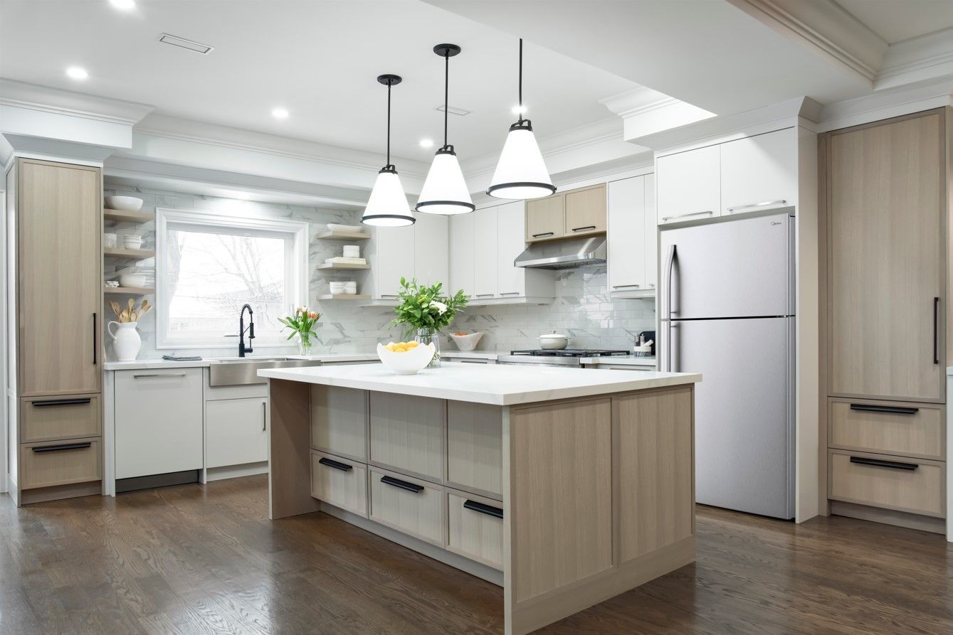 Modern kitchen with white cabinets, island, stainless steel appliances, and wooden floors.