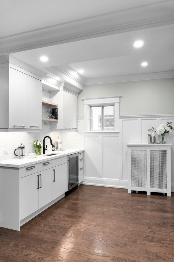 White kitchen with cabinetry, stainless steel appliances, and dark hardwood floors.