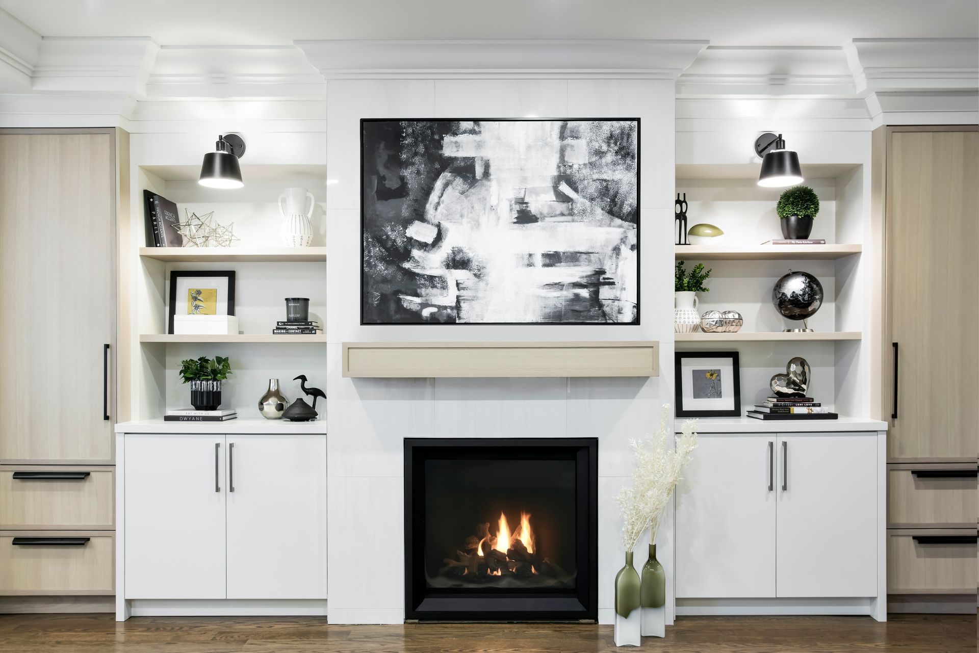 Fireplace with built-in shelves, artwork, and cabinets. Black and white, modern design.