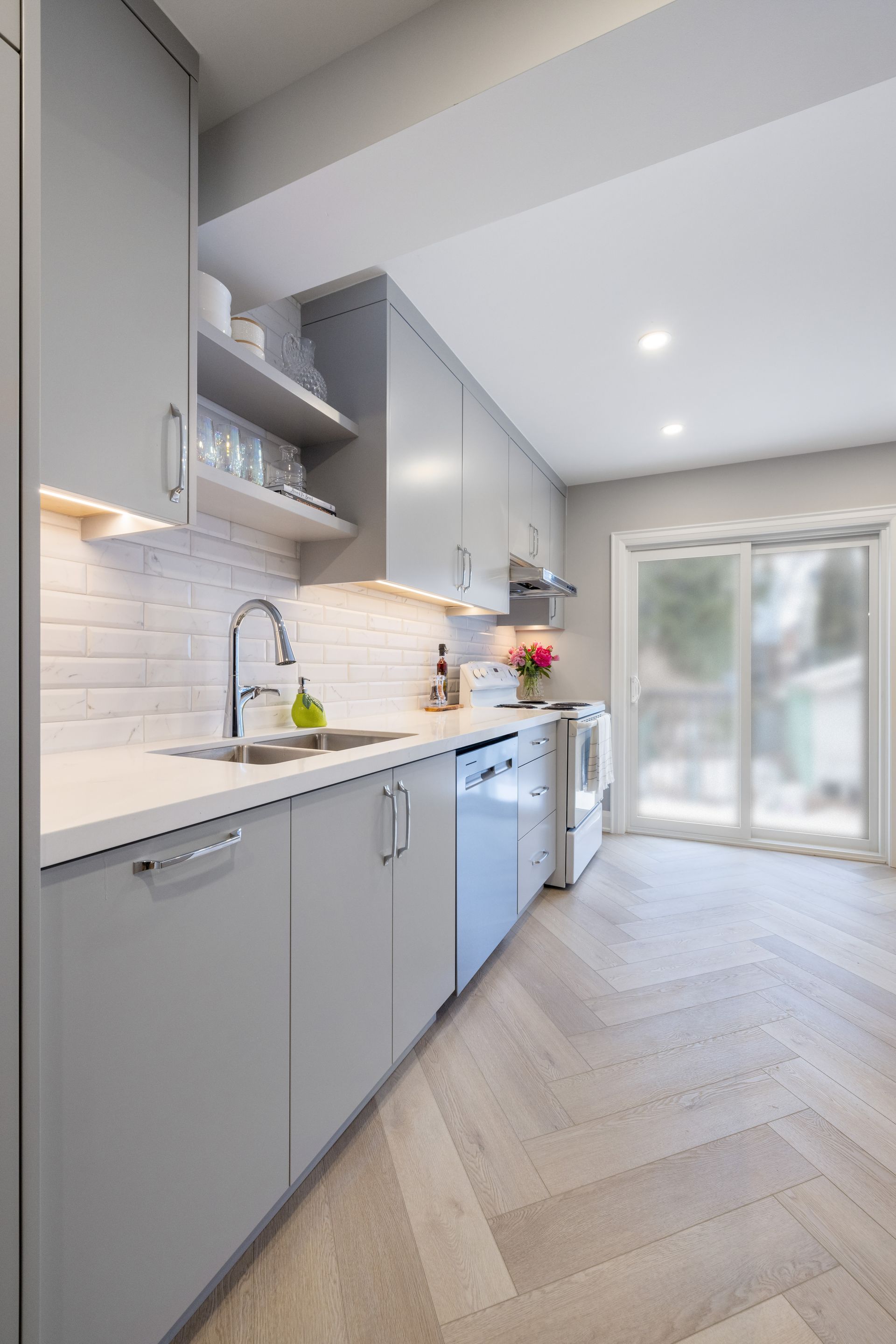 Gray modern kitchen with cabinetry, appliances, white countertops, and sliding glass door.