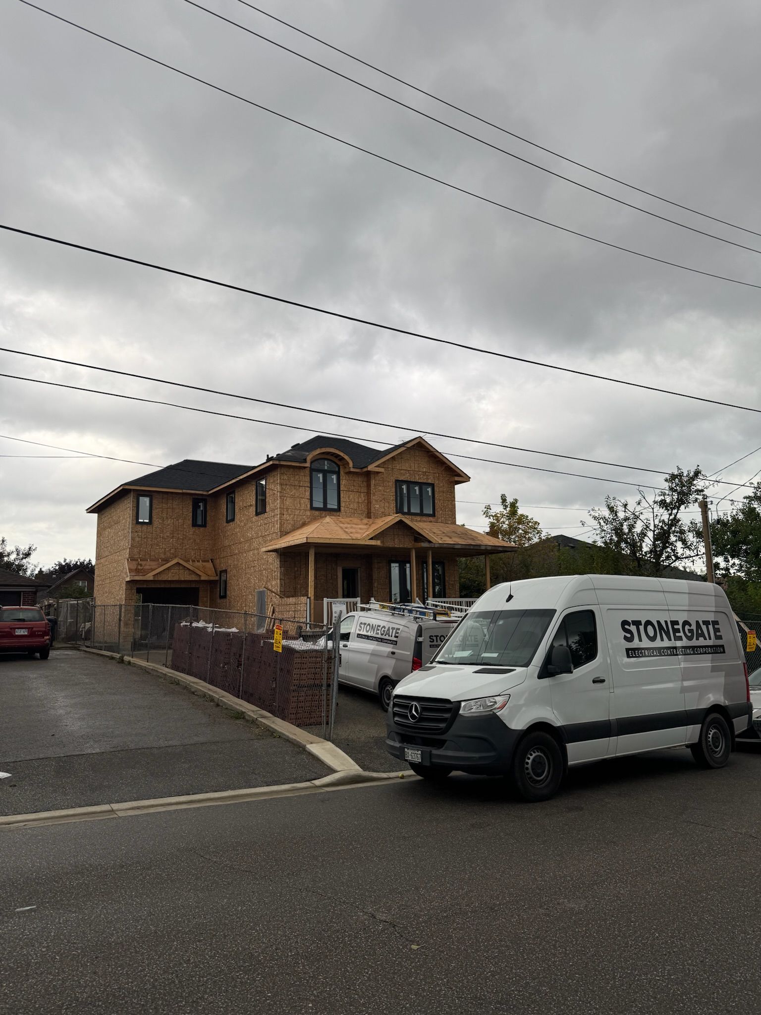 Brick house under construction with a white van in the driveway. Overcast sky.