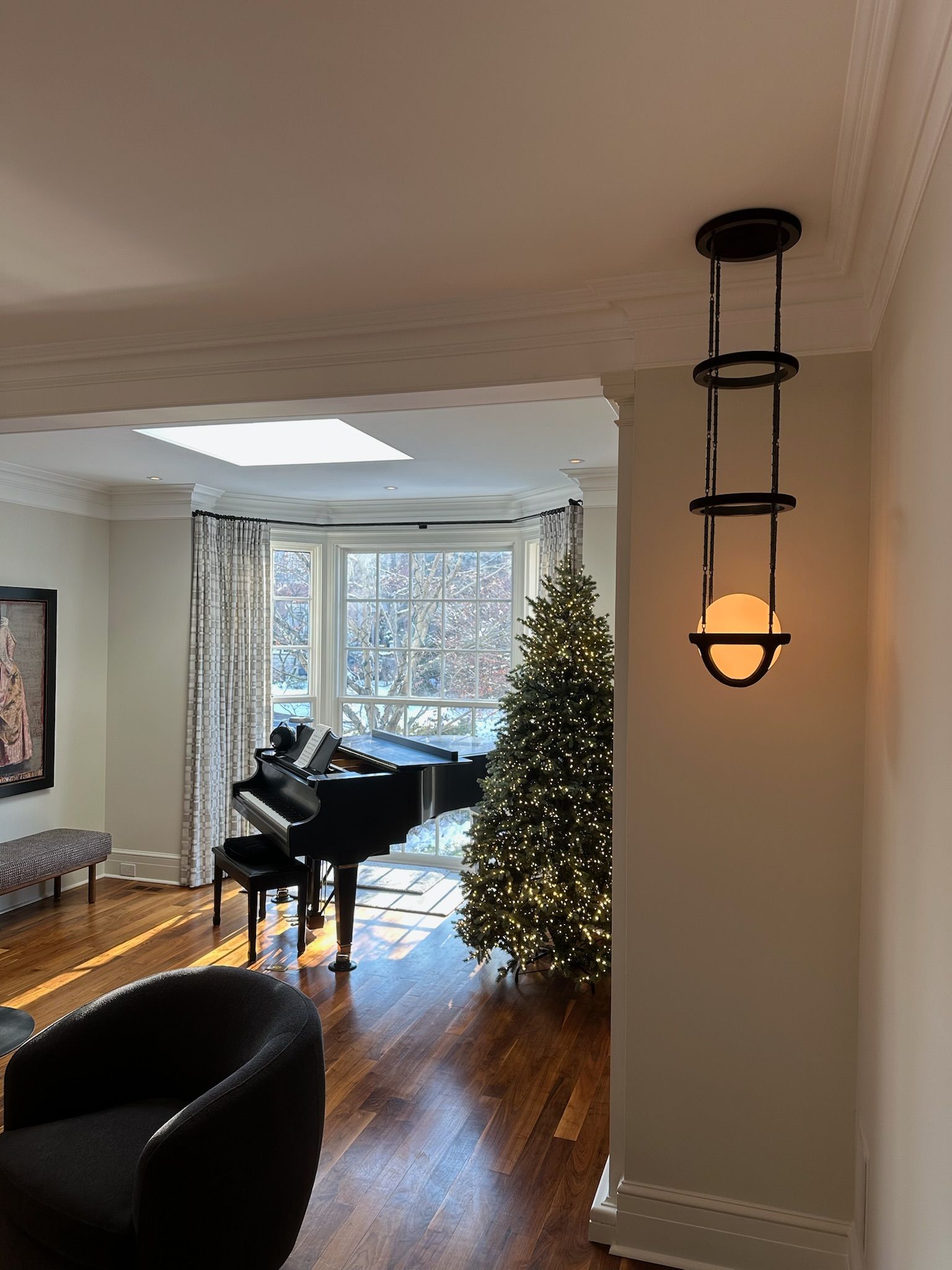 Living room with a piano, Christmas tree, and decorative hanging light.