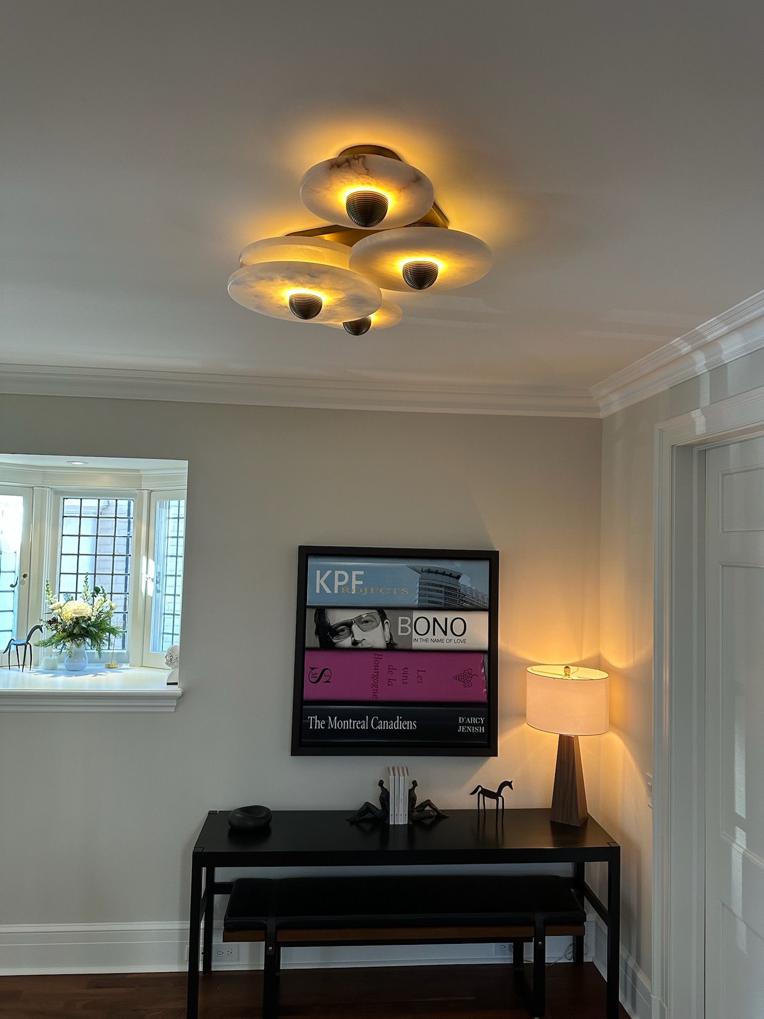 Ceiling light fixture with cloud-like shades above a desk with a magazine rack and lamp.