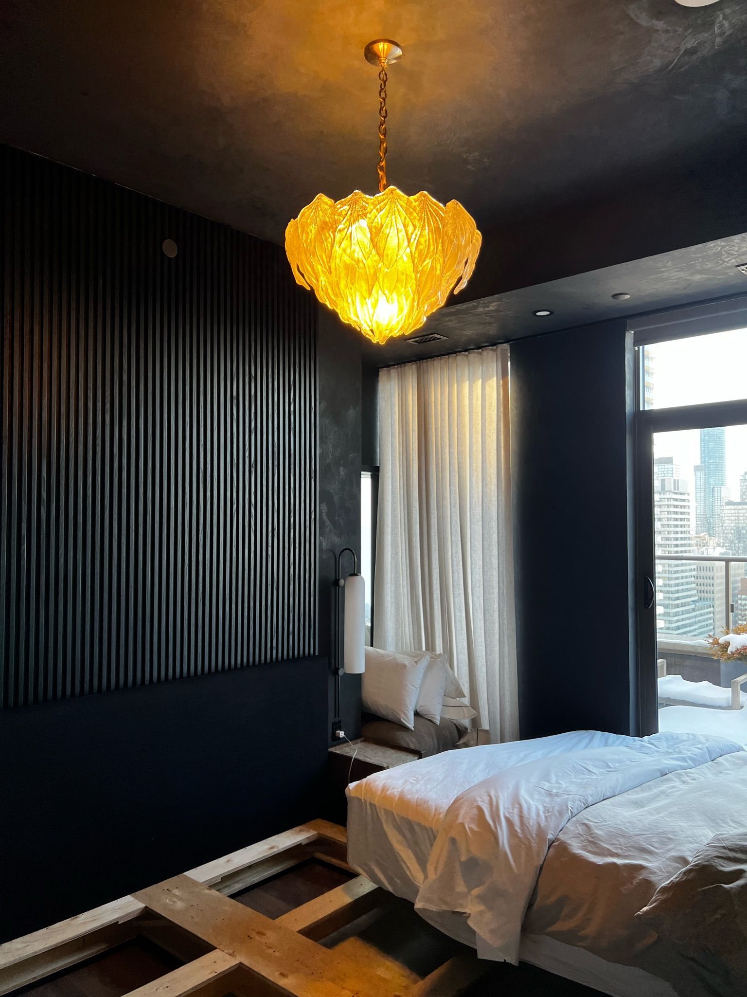 Dark room with a massage table, window, and ornate amber chandelier.