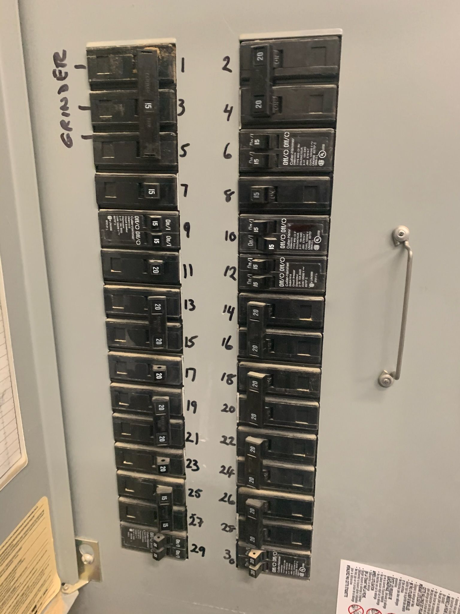 Electrical circuit breaker panel, gray metal, labeled circuits. Breakers in on/off positions.
