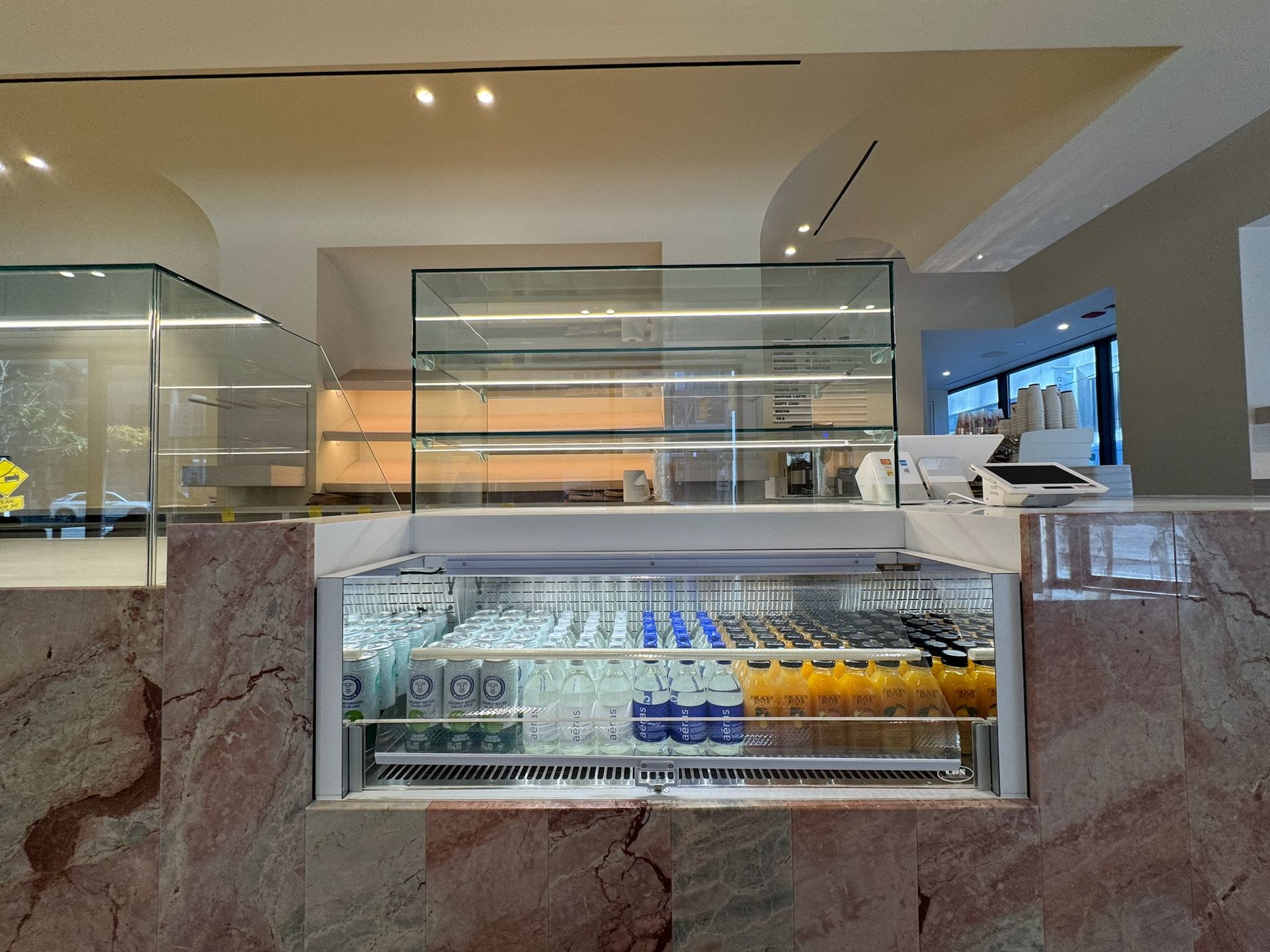 Cafe display case filled with drinks, food items, and equipment; set in a building with marble and bright lights.