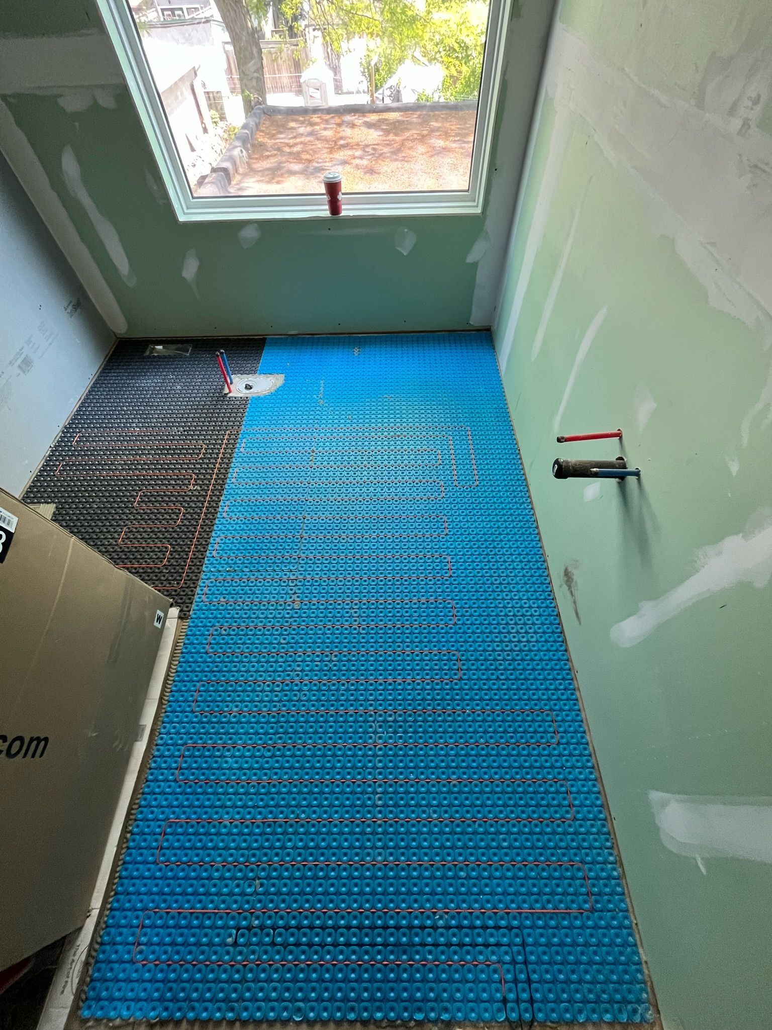 Blue underlayment on floor in room with unfinished walls and skylight.