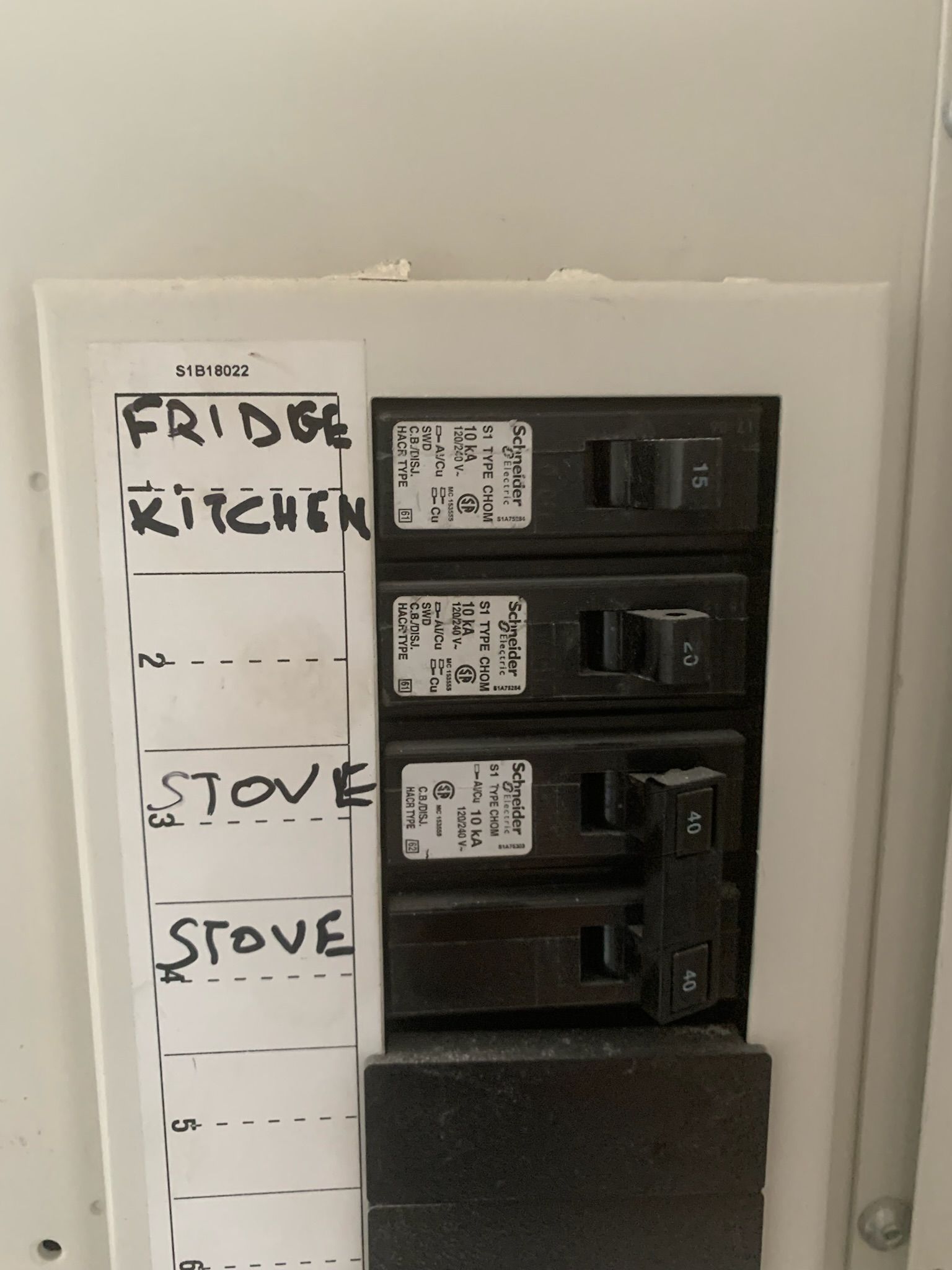 White electrical breaker box labeled: fridge, kitchen, stove, stove. Some breakers are flipped.