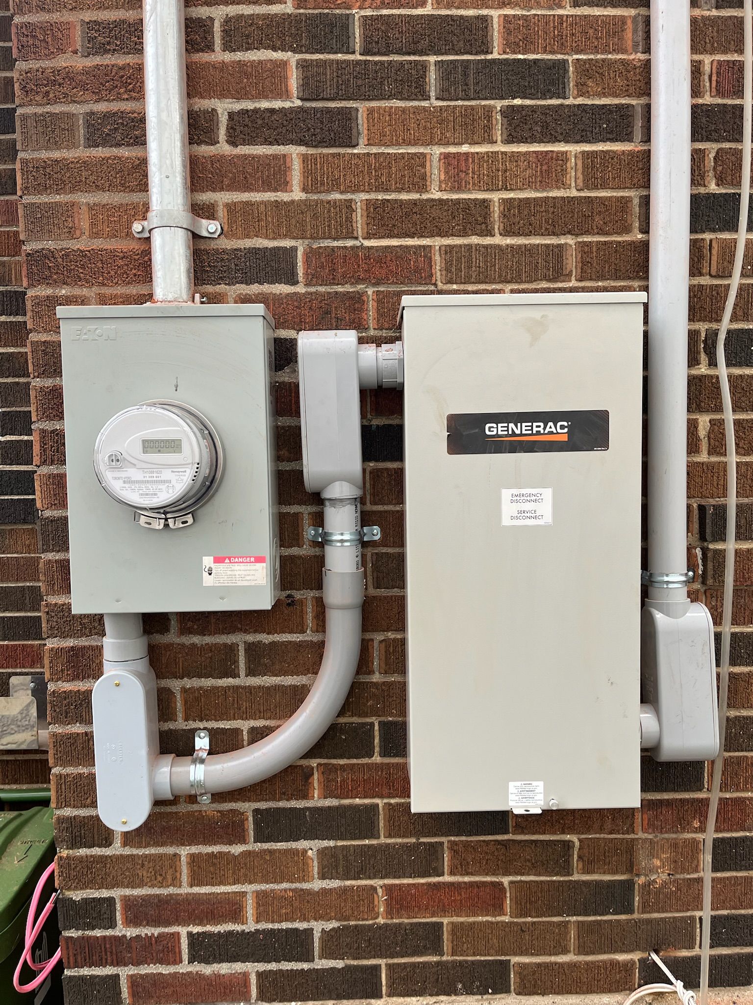 Electrical meter and panel on a brick building's exterior, with conduits.