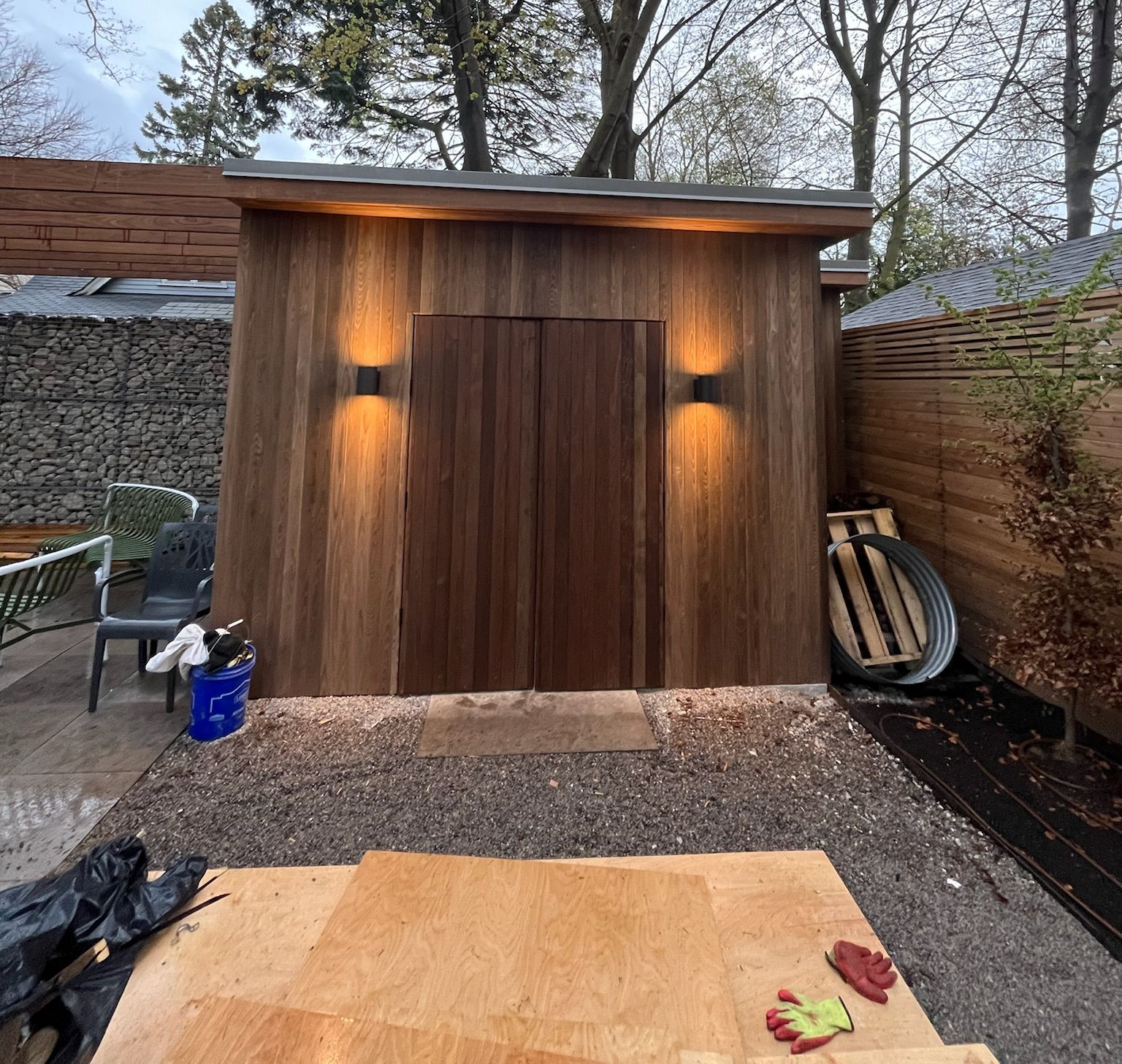 Wooden shed with double doors, two lights, and gravel flooring.