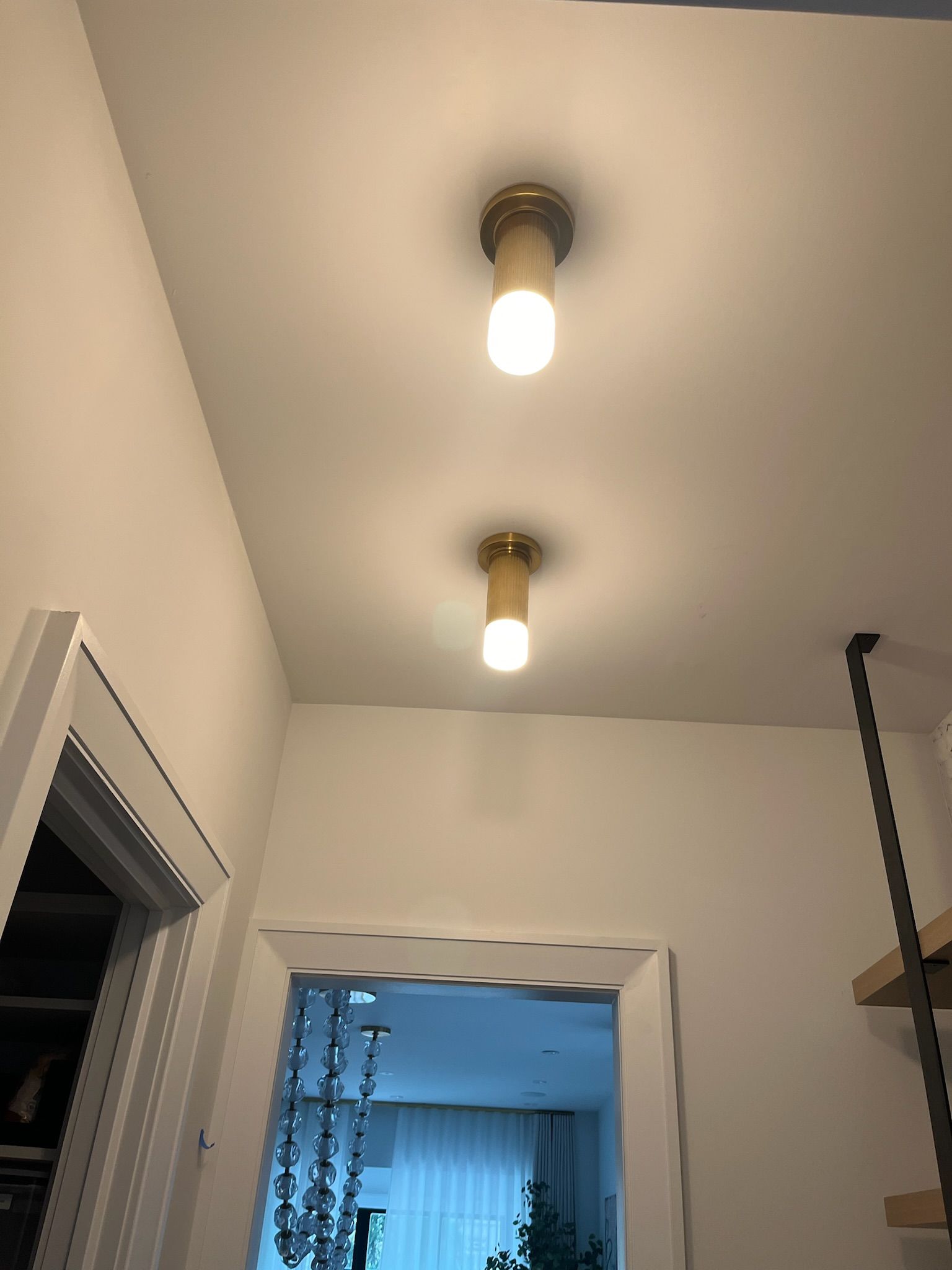 Two ceiling lights illuminate a white hallway.