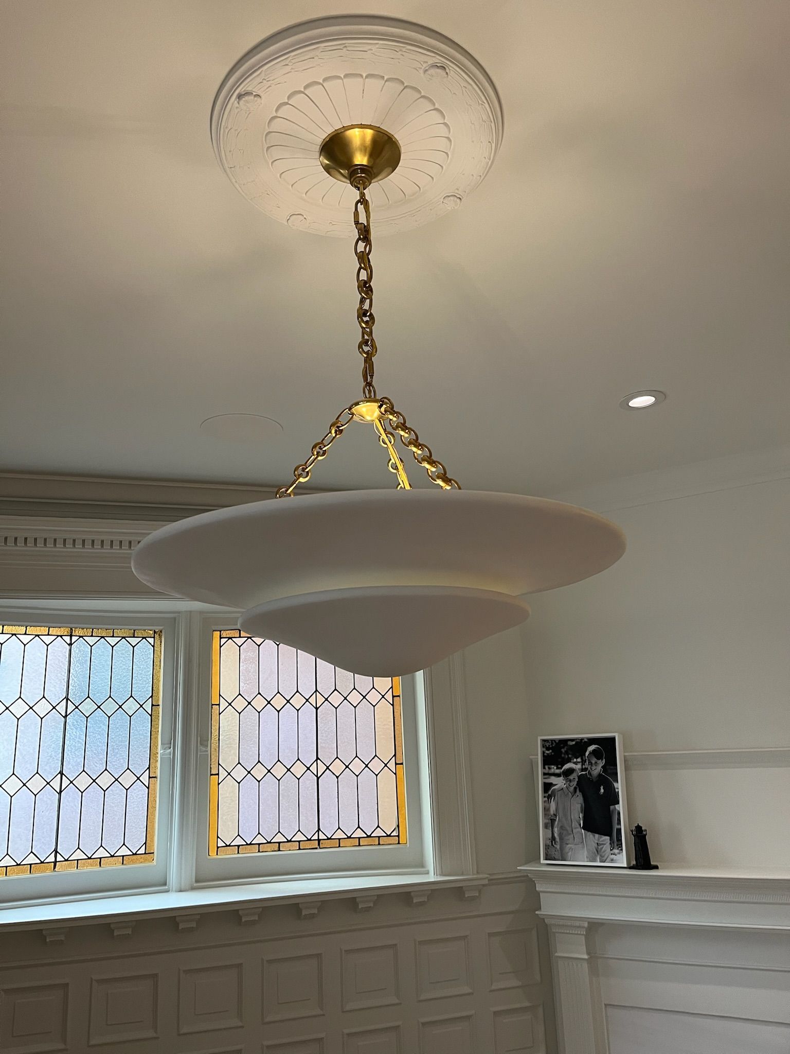 A white layered pendant light hanging from a decorative ceiling medallion.