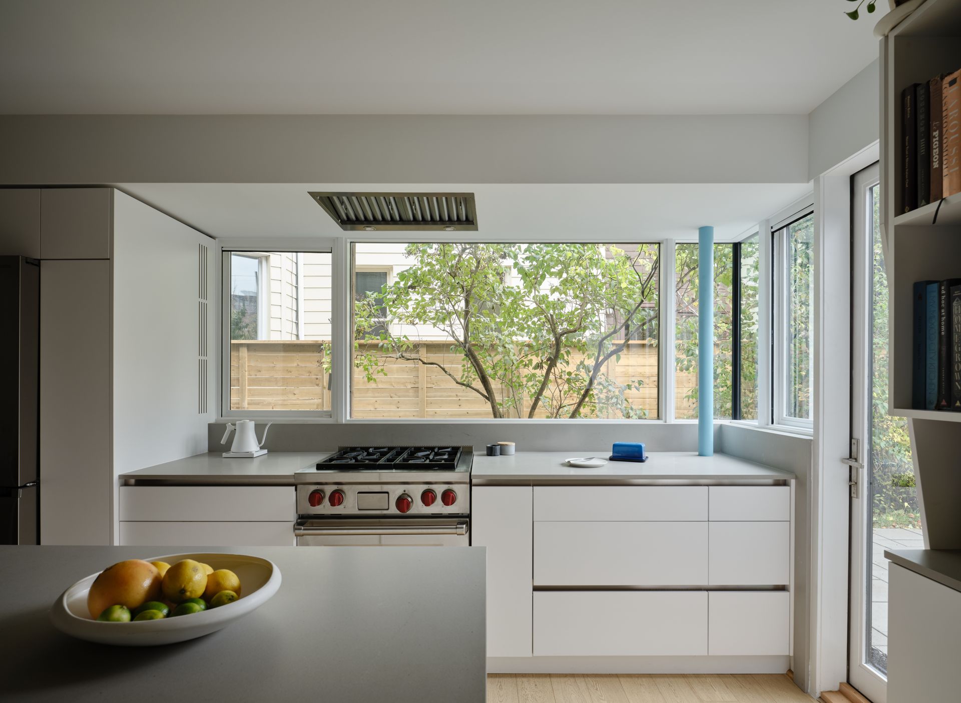 Dark exterior with open lit doorway, chairs on patio, and foliage.